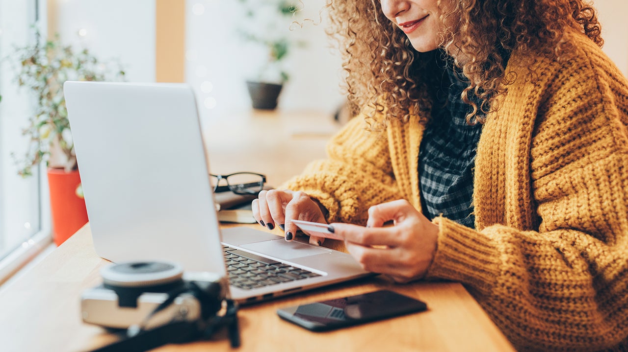 Woman sitting at a computer and holding a credit card