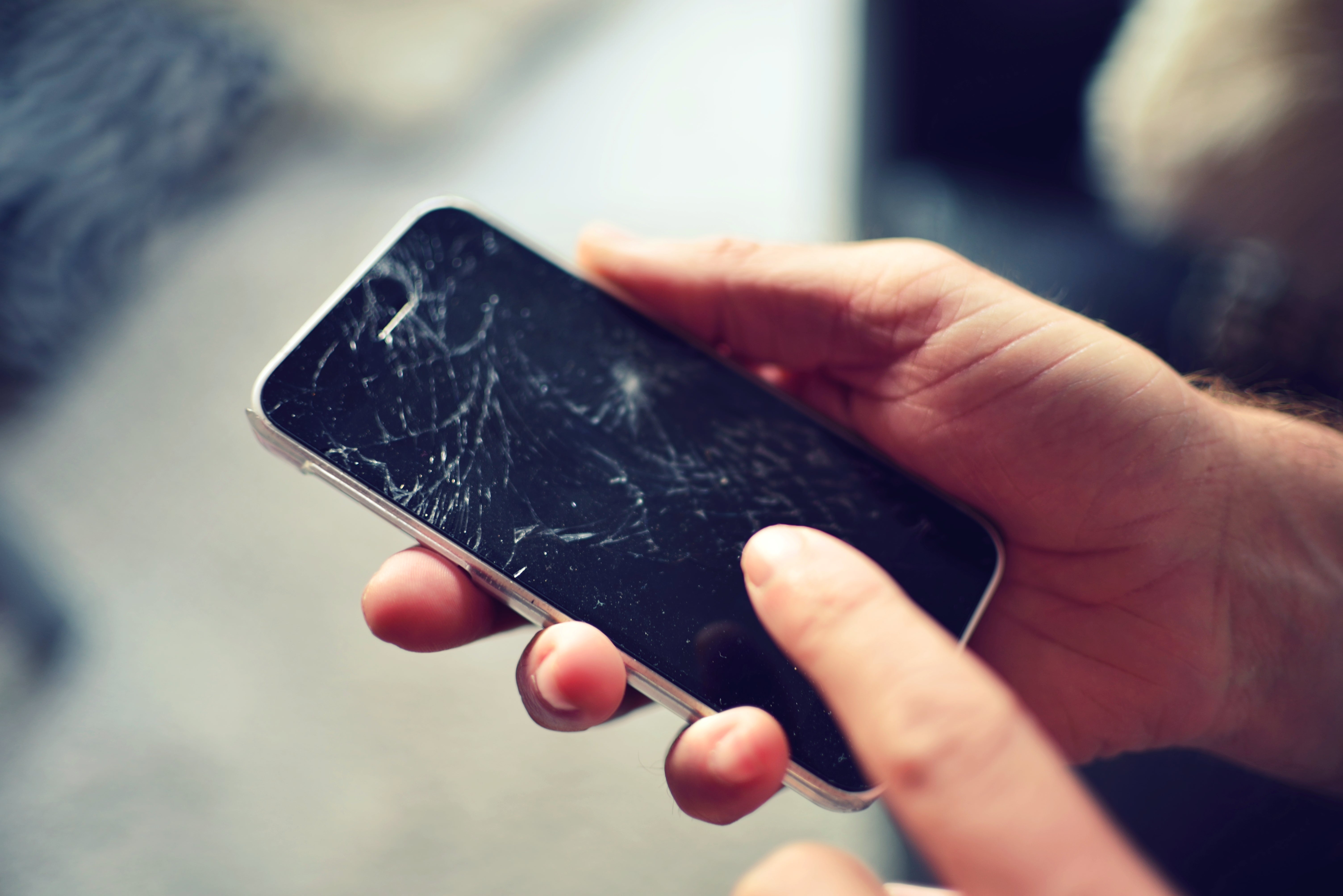 two hands hold a smartphone with a cracked screen