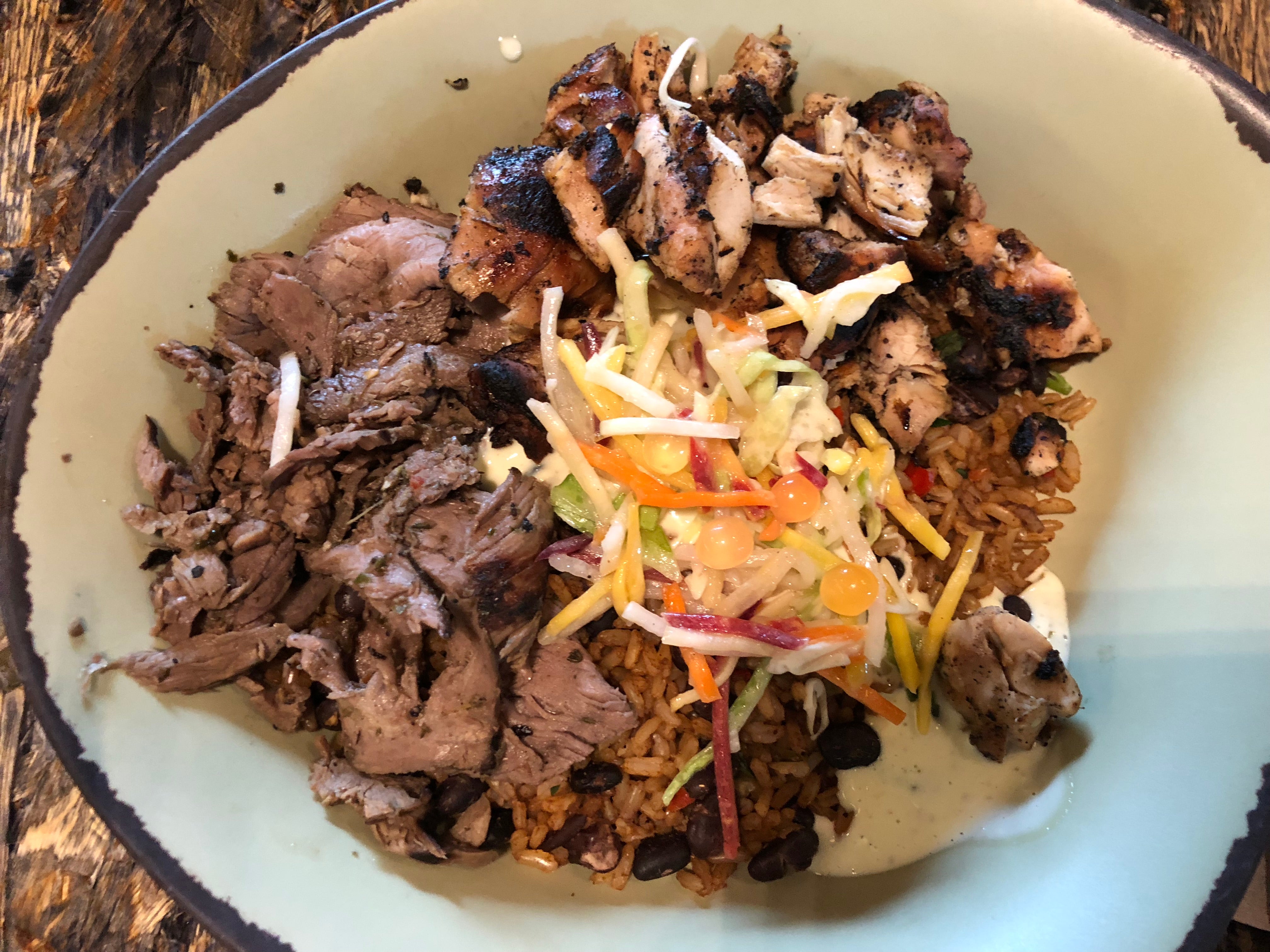 A bowl of chopped beef and chicken topped with vegetable slaw and orange boba at Satuli Canteen at Animal Kingdom at Walt Disney World