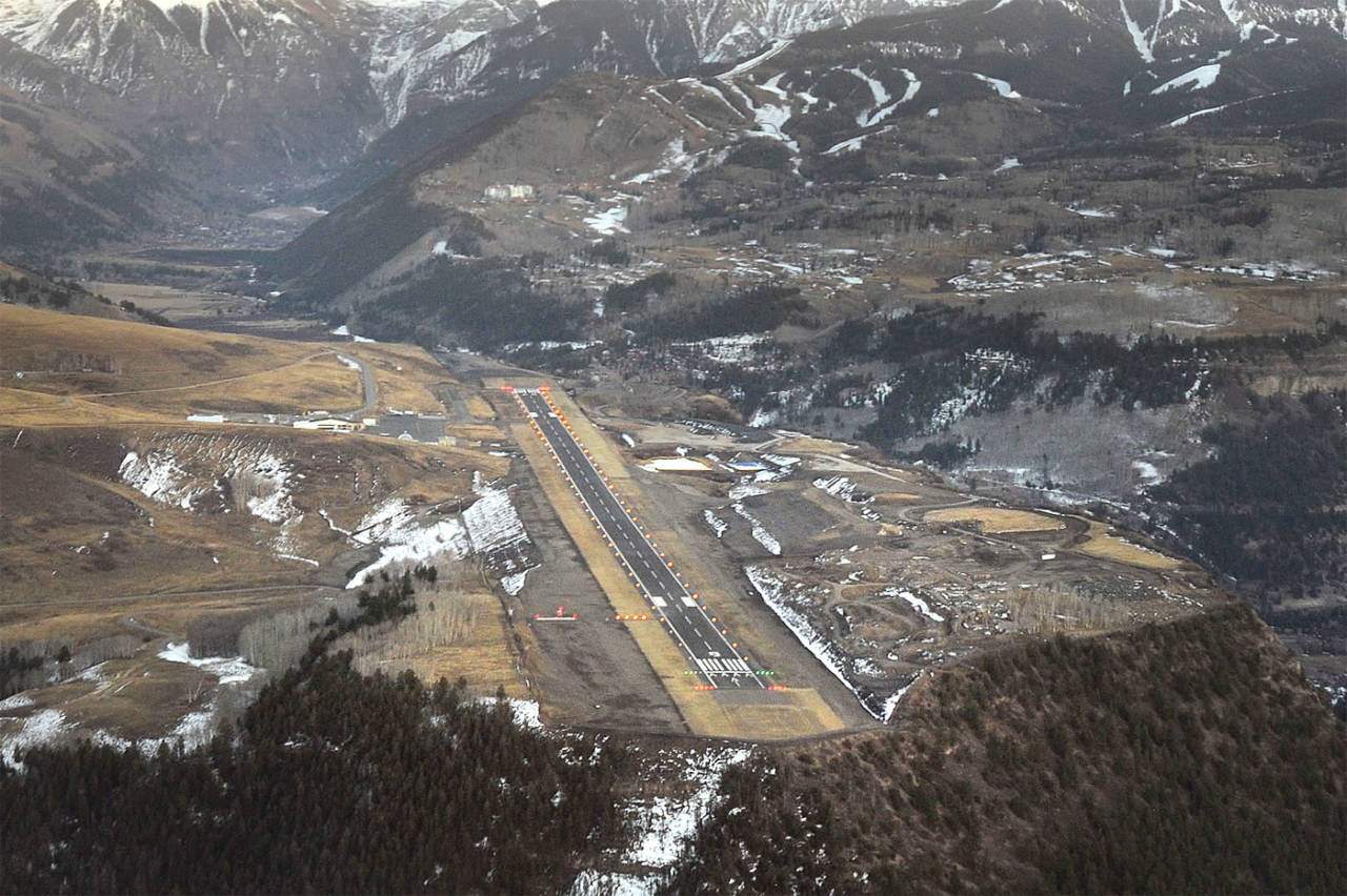 an overhead view of an airport runway surrounded by mountains