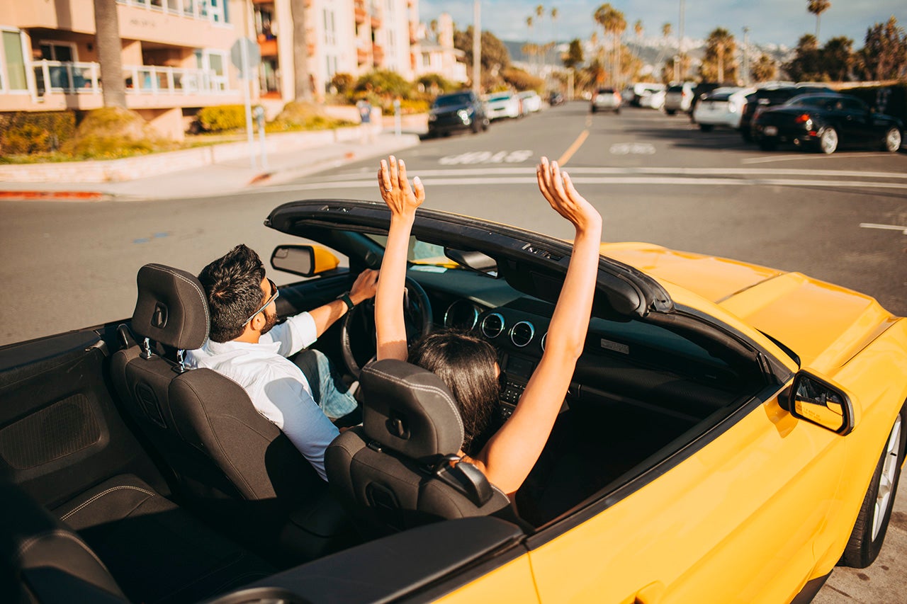 two people drive a yellow convertible car with the top down