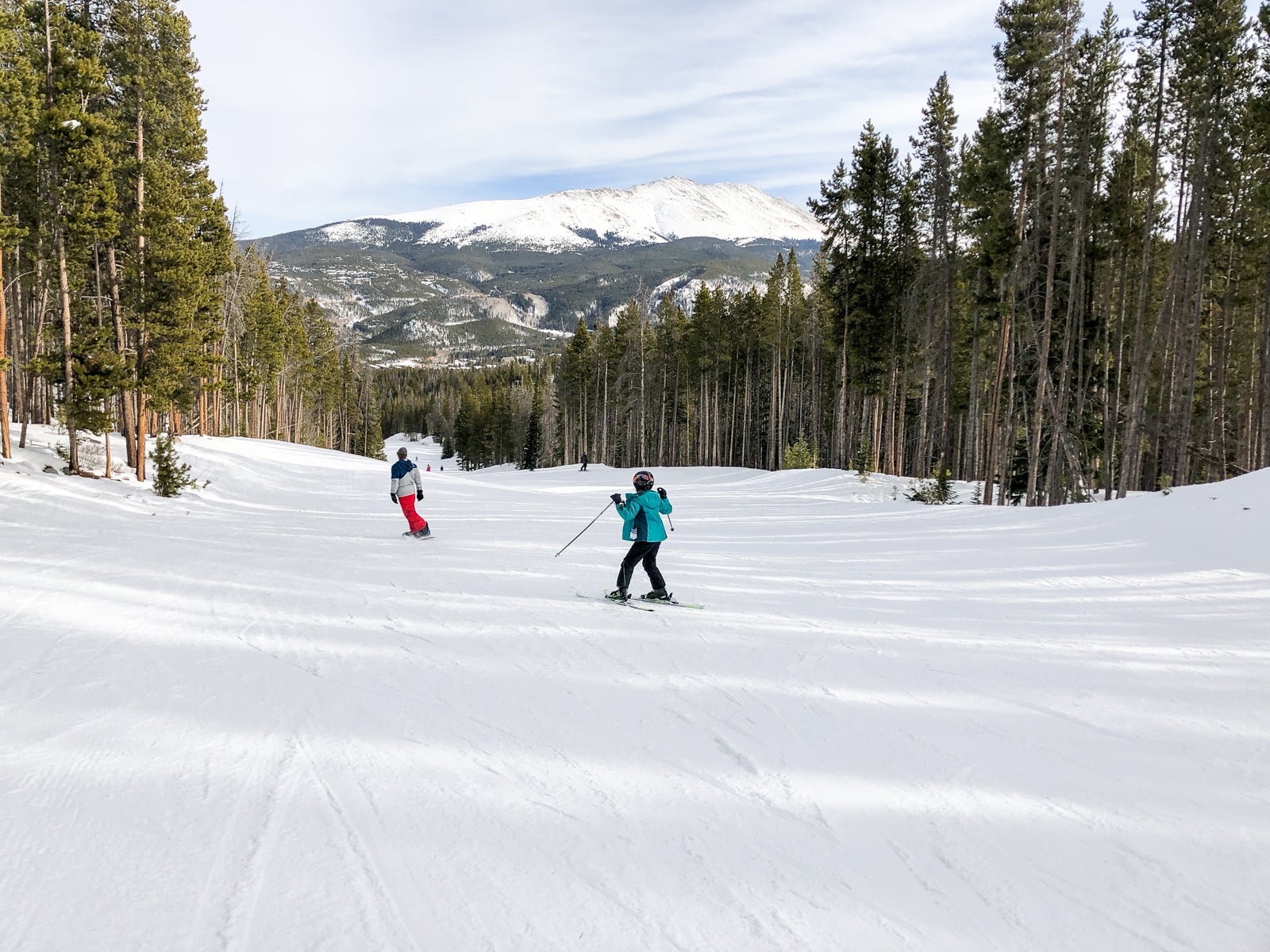 Skier and snowboarder glide down a mountain