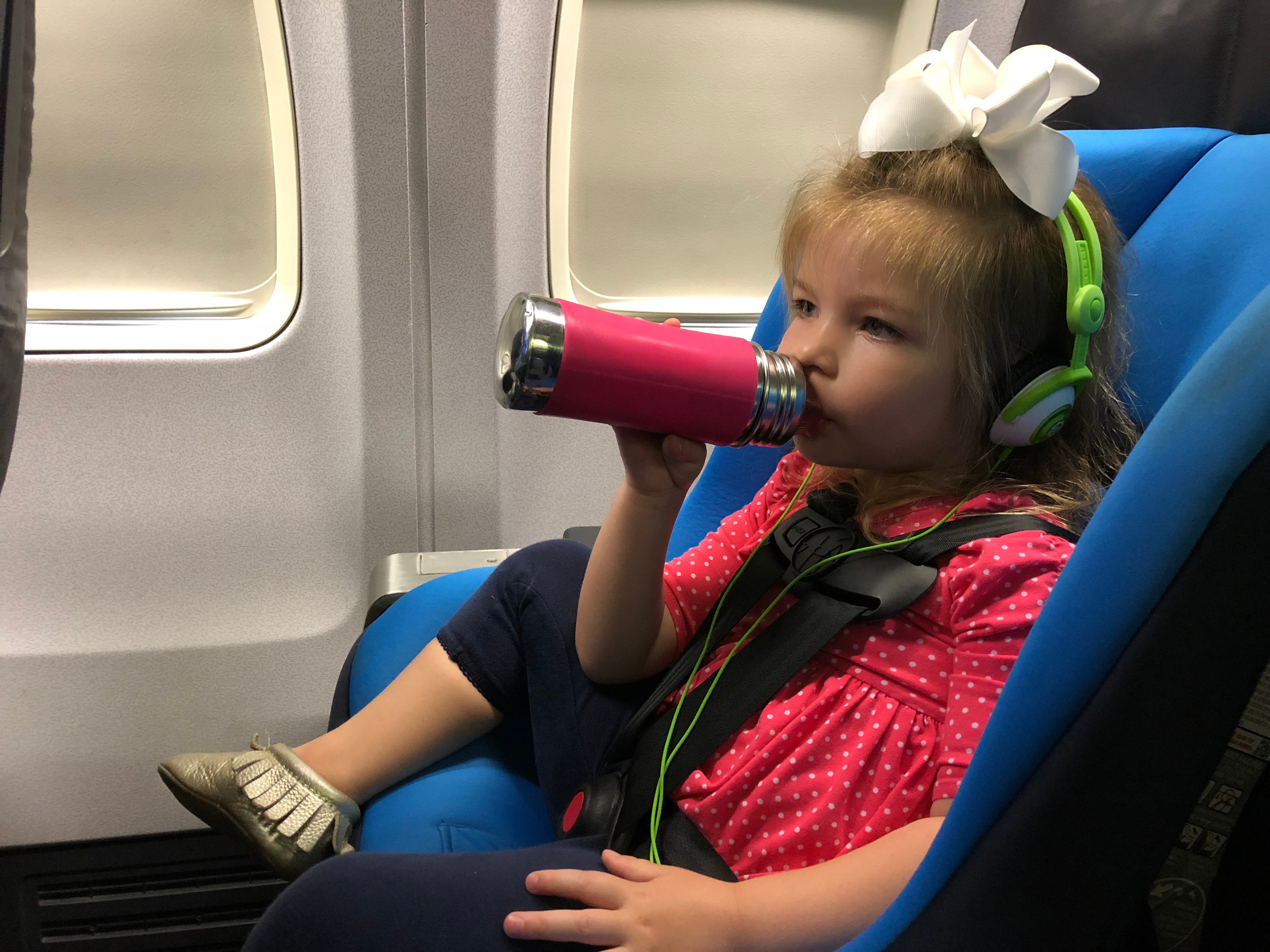 A child drinking from a water bottle on a plane 