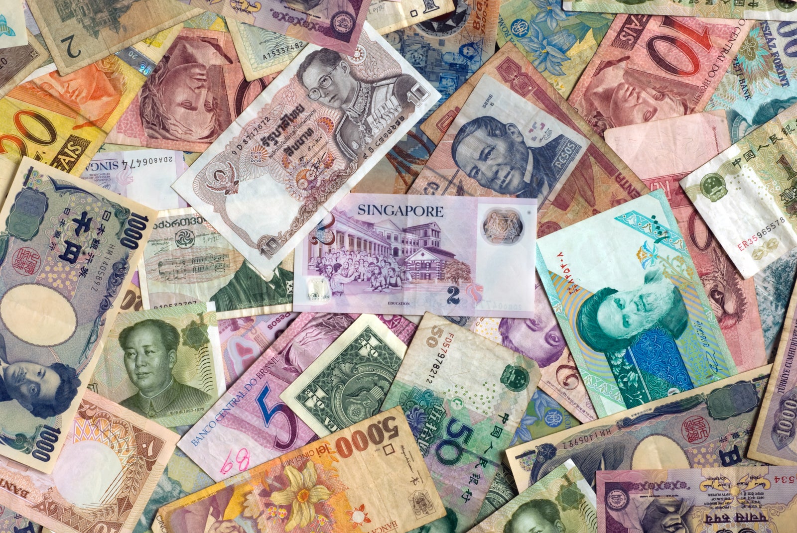 Different paper currencies on top of one another in a colorful layout