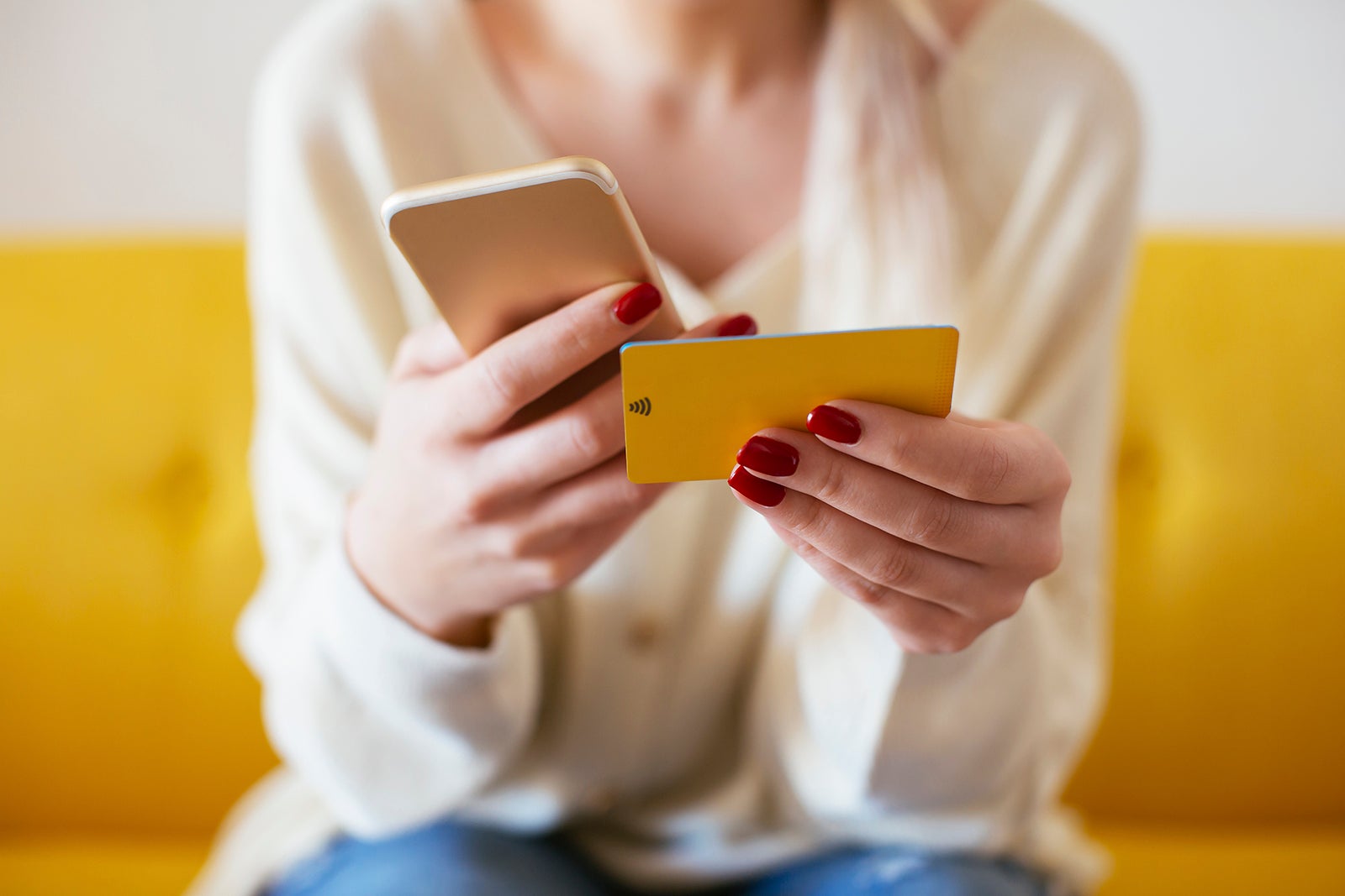 A person holds a credit card while looking at their phone