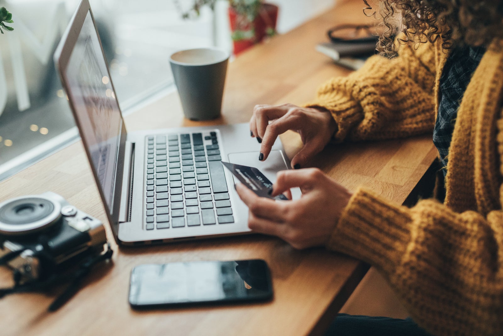 Woman holding credit card while typing on a laptop