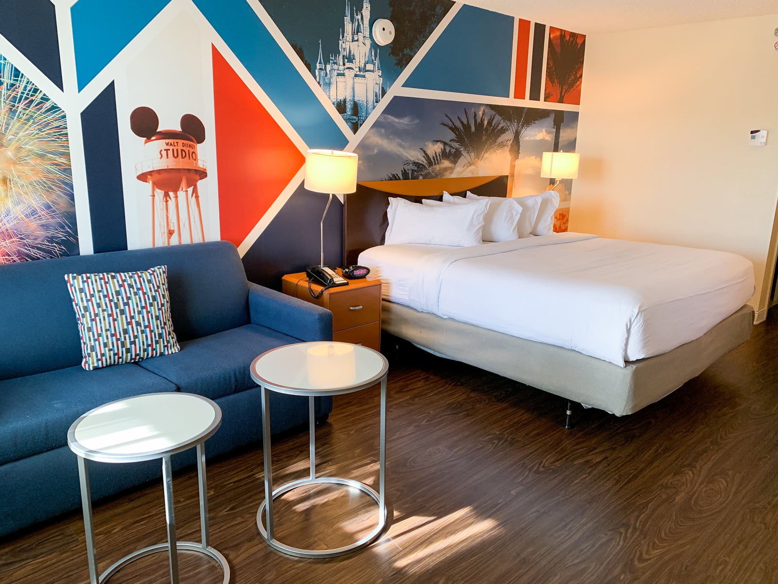 A hotel room at the Fairfield Anaheim Resort with a bed, sofa and bright blue and red decor