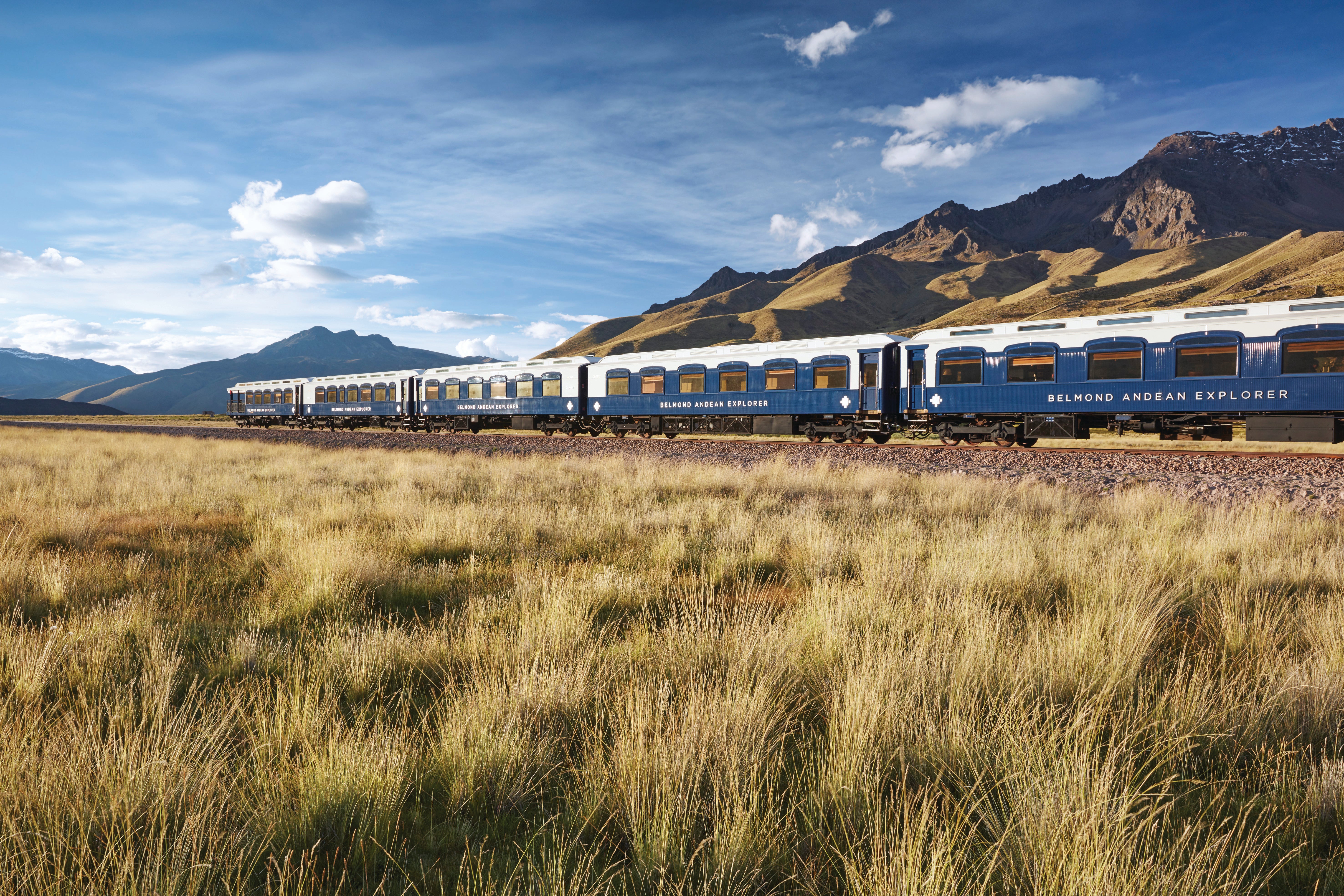 train traveling between grassland and mountains
