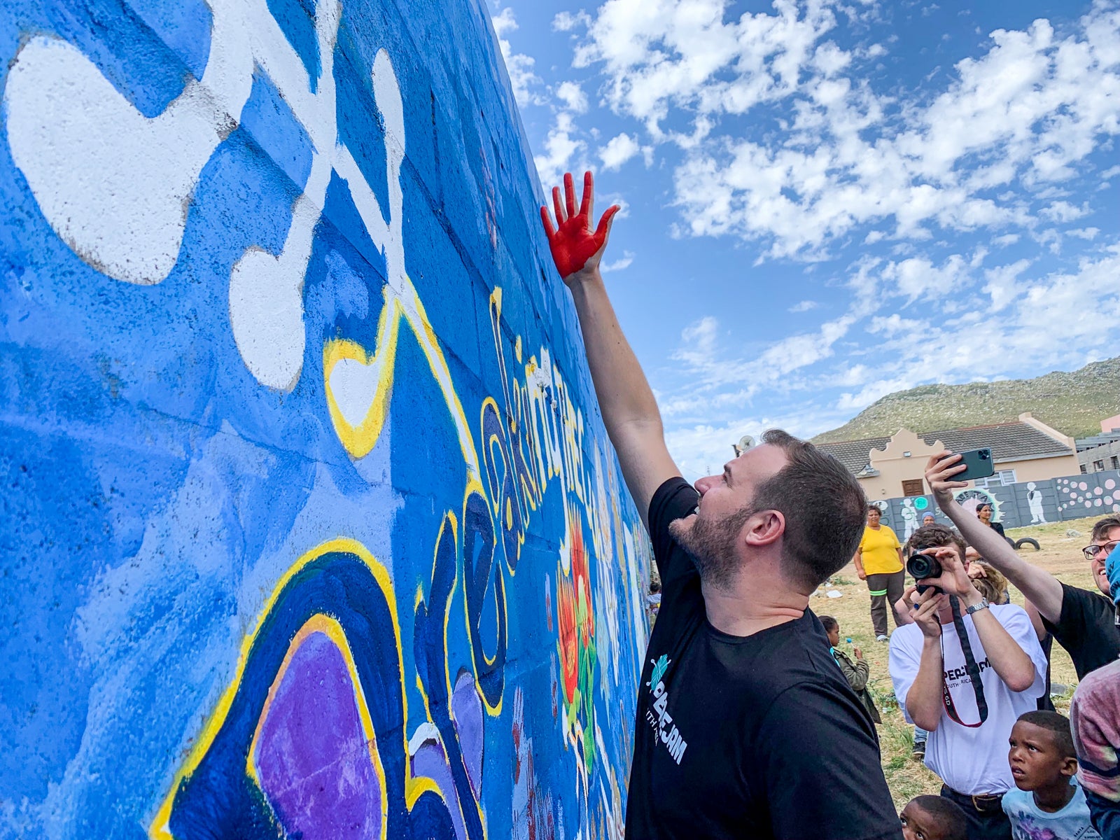 TPG's Brian Kelly places a red handprint on a mural in South Africa during a Peace Jam Conference.
