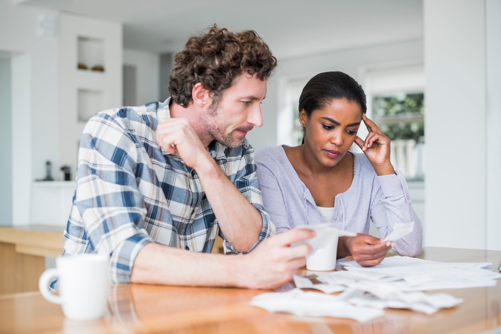 Tensed multi-ethnic couple reading bills at home.