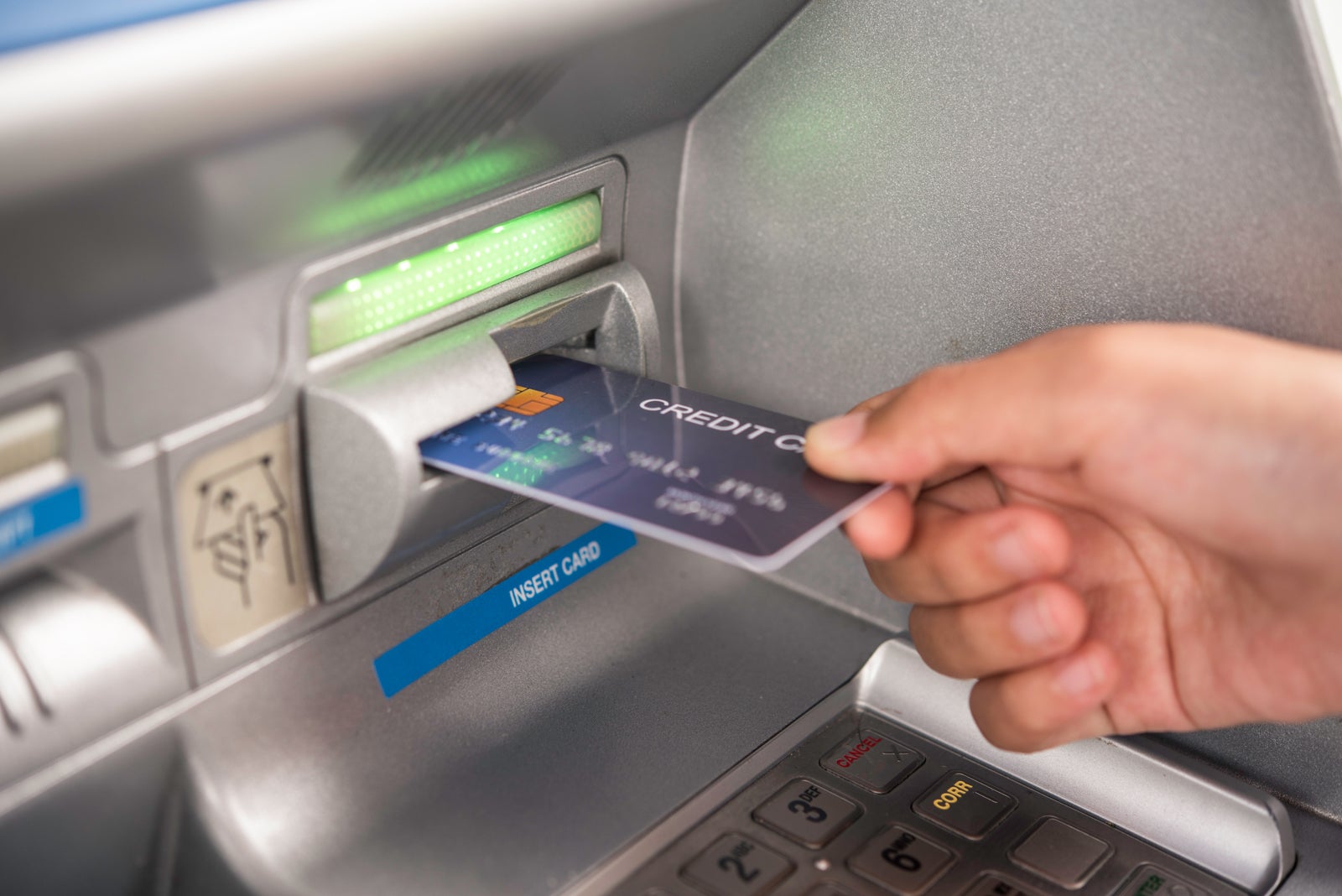 A hand putting a bank card into an ATM