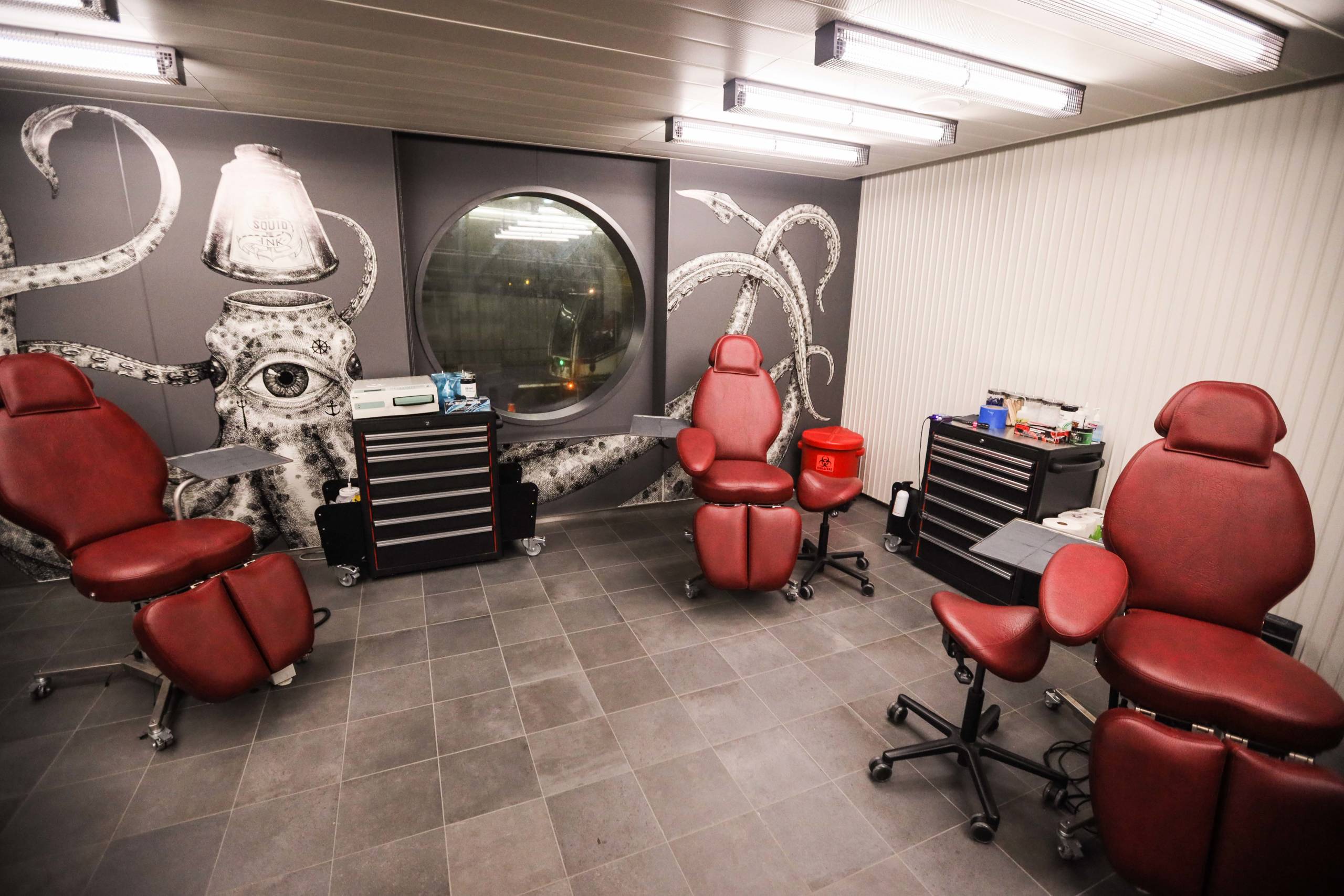 The inside of a cruise ship tattoo parkoer with a squid painted on the wall and two red chairs