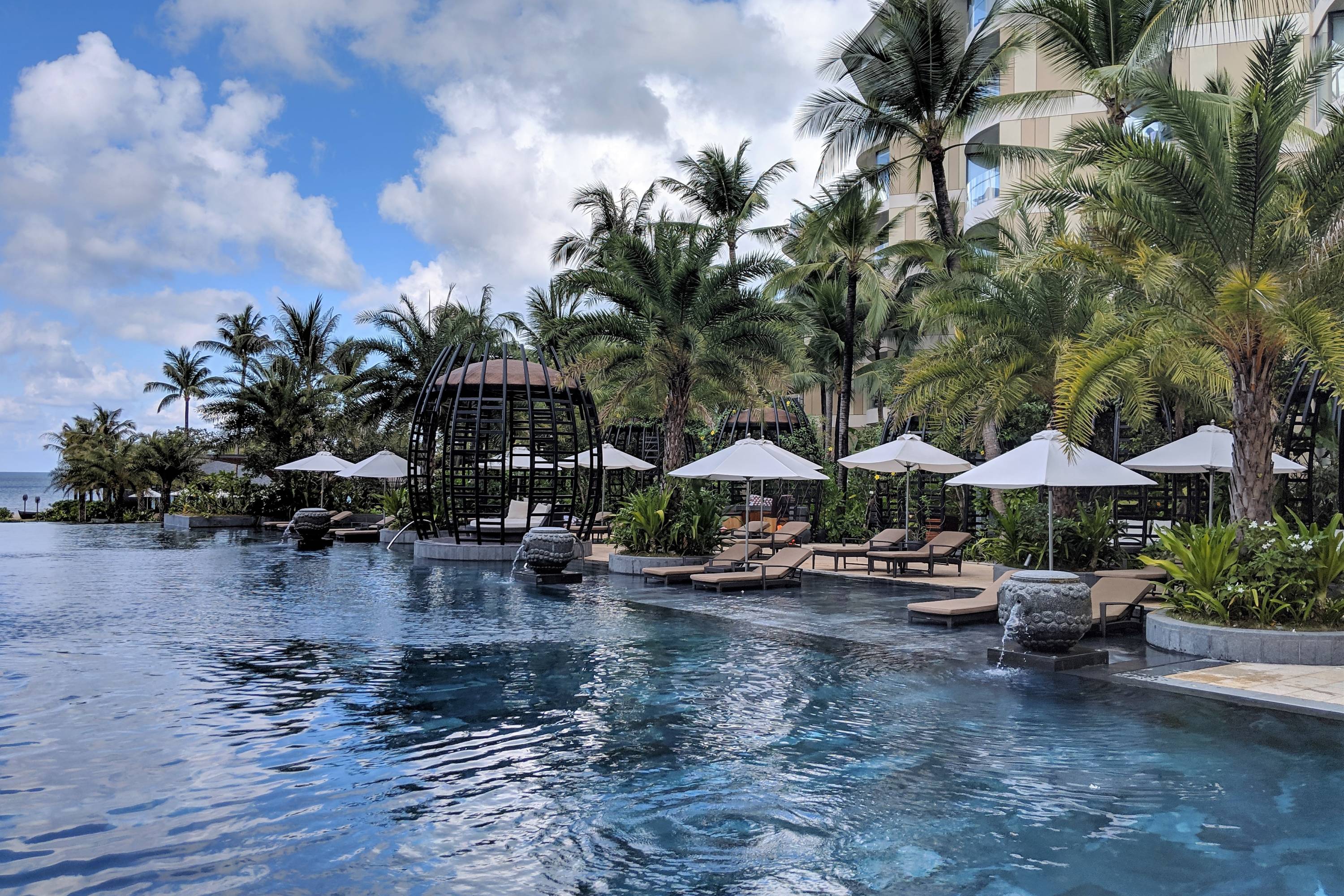 a hotel pool and cabanas surrounded by palm trees