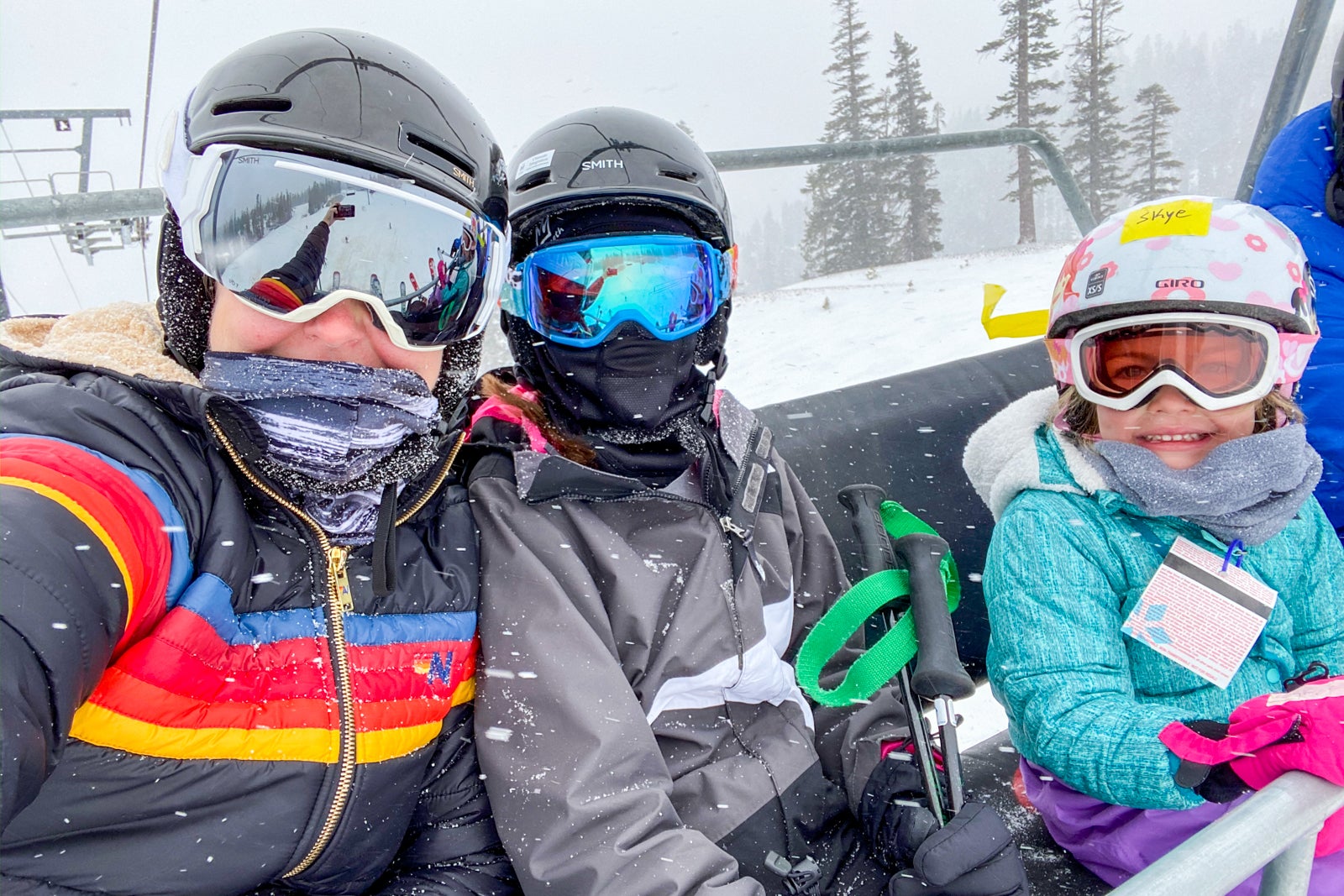 two adults and child in ski gear on lift