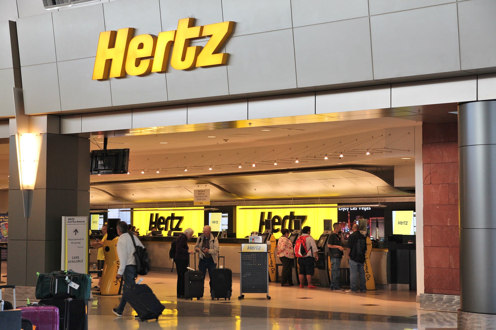 travelers with luggage at Hertz counter