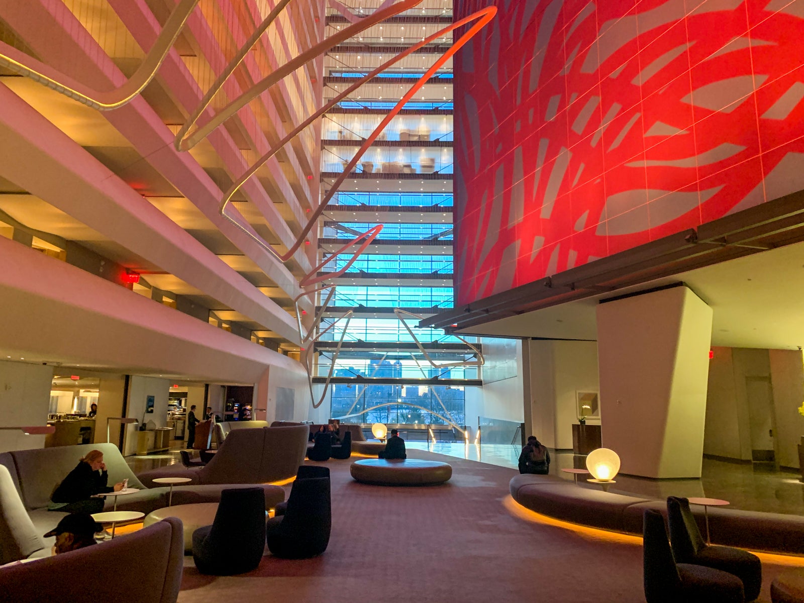 a vaulted hotel lobby shows furniture but also numerous art displays hanging over the guests below