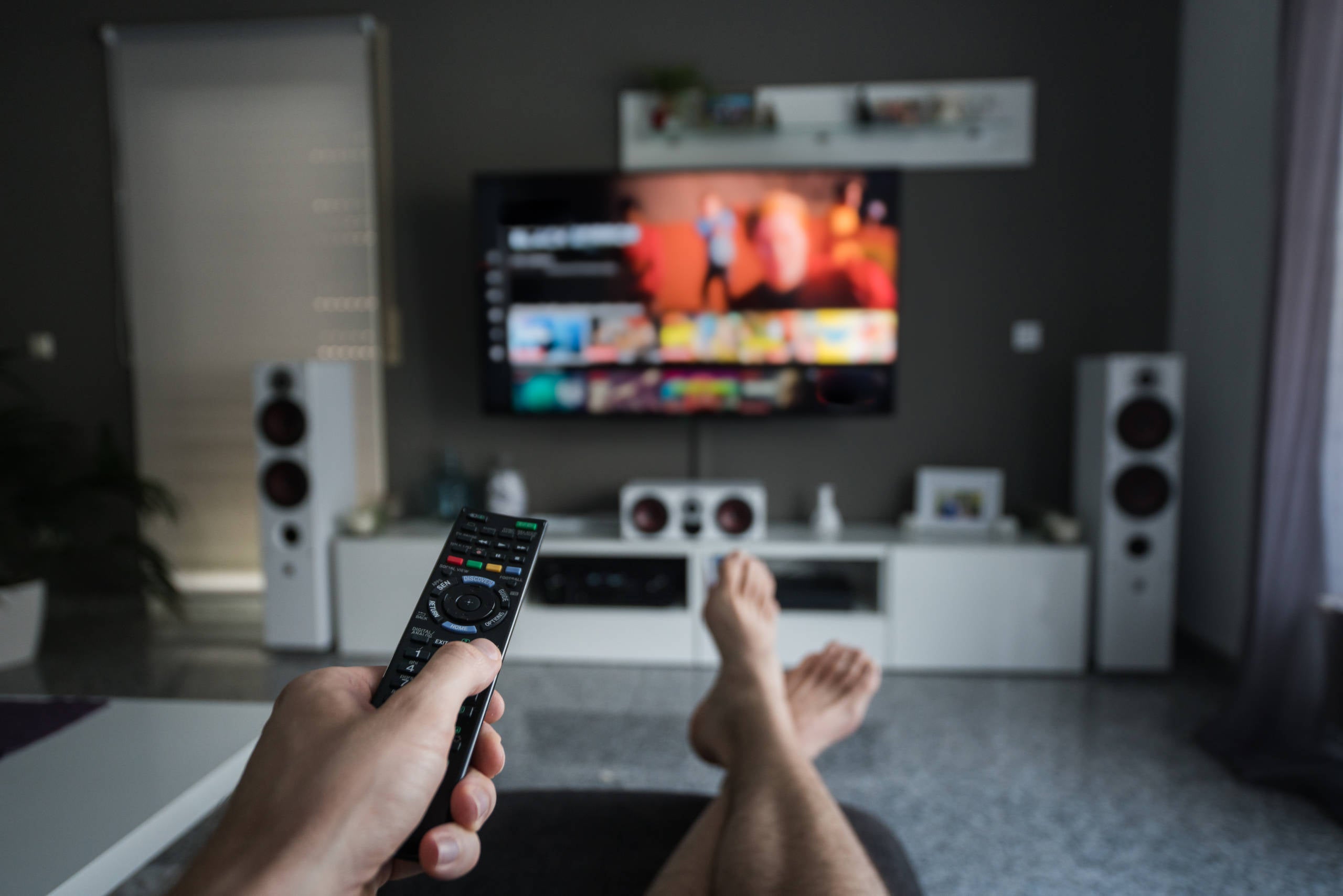 an unseen person is watching TV and holding a remote