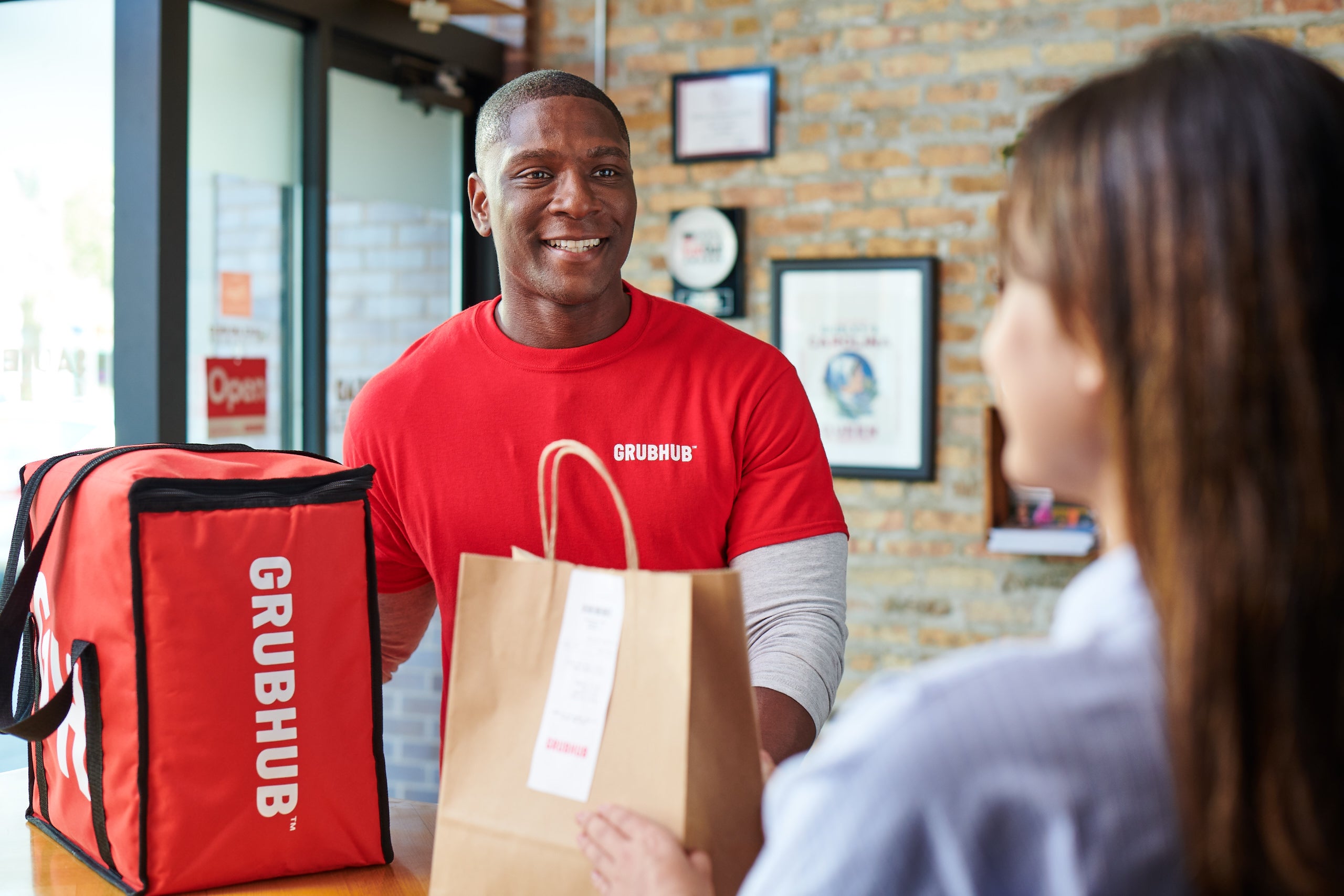 a delivery driver picks up a bag of food from inside a restaurant