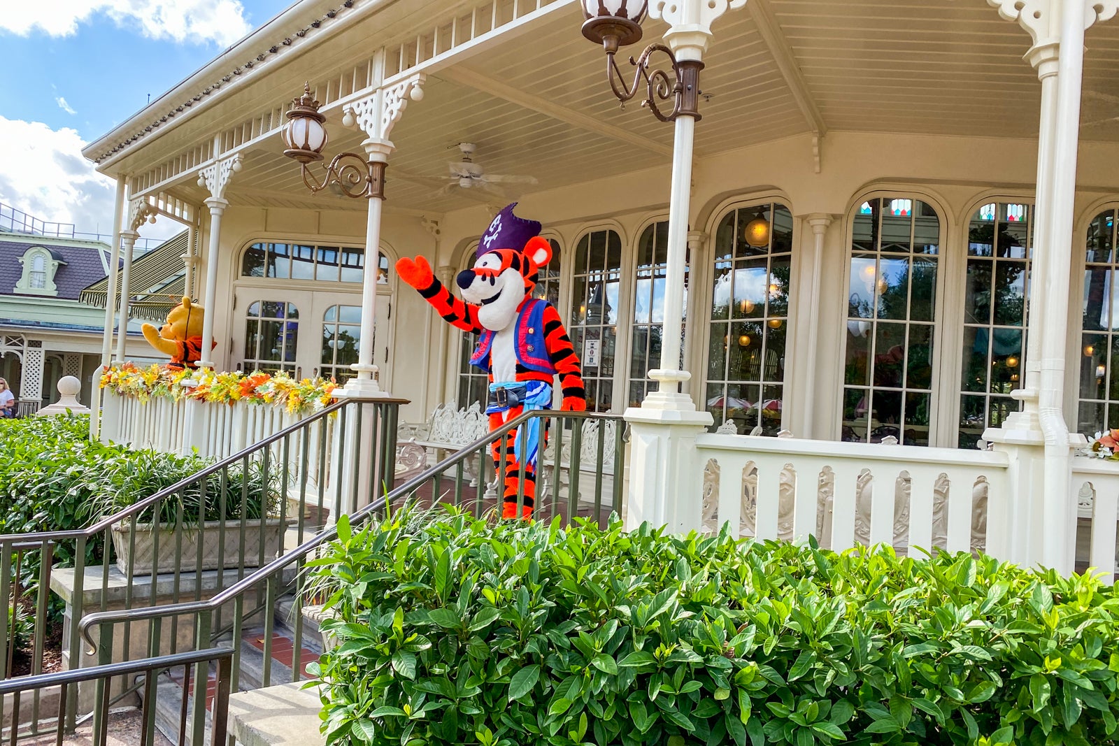 A person dressed up as Tigger in a pirate costume waves from the porch of The Crystal Palace in Walt Disney World