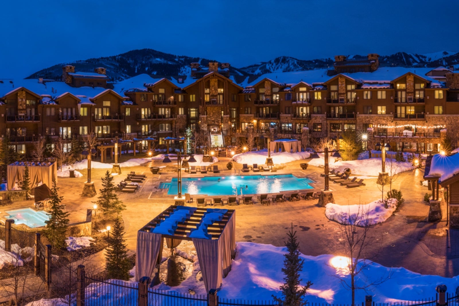 lit pool and hotel with snowy mountains in background