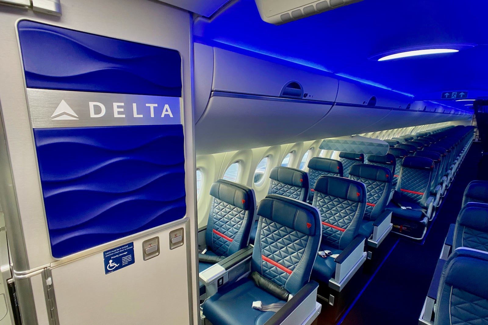 a Delta sign next to empty economy seats on a plane
