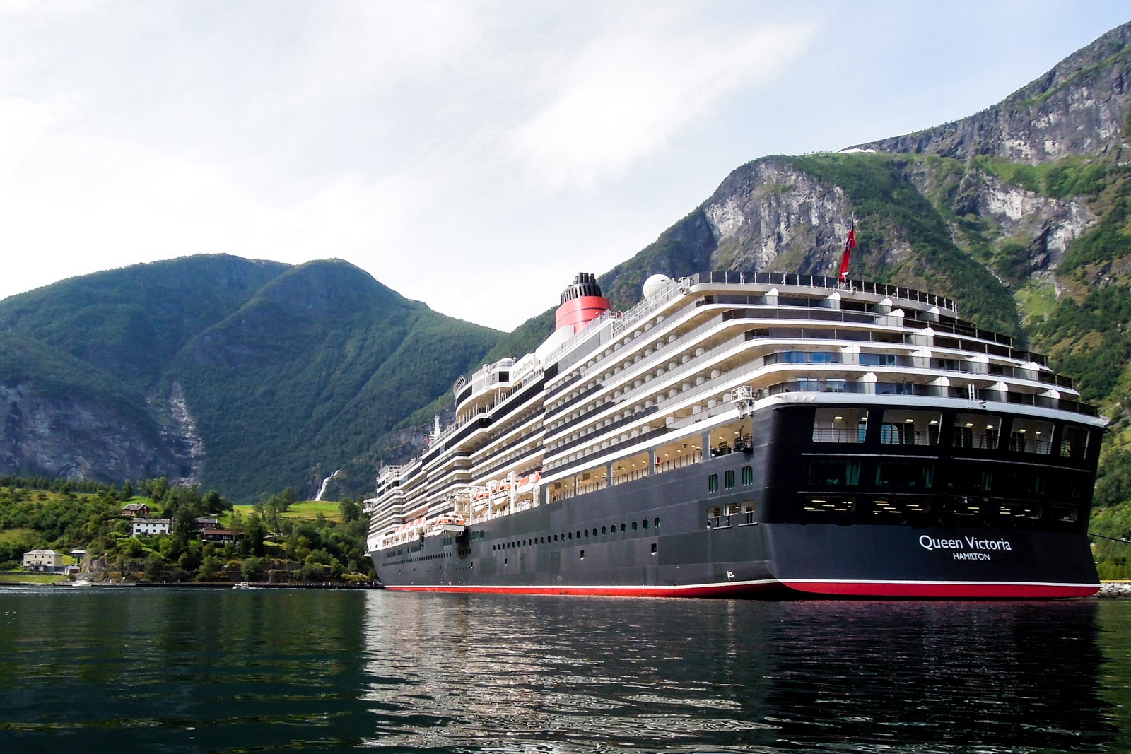 A rear side view of a Cunard cruise ship near mountains