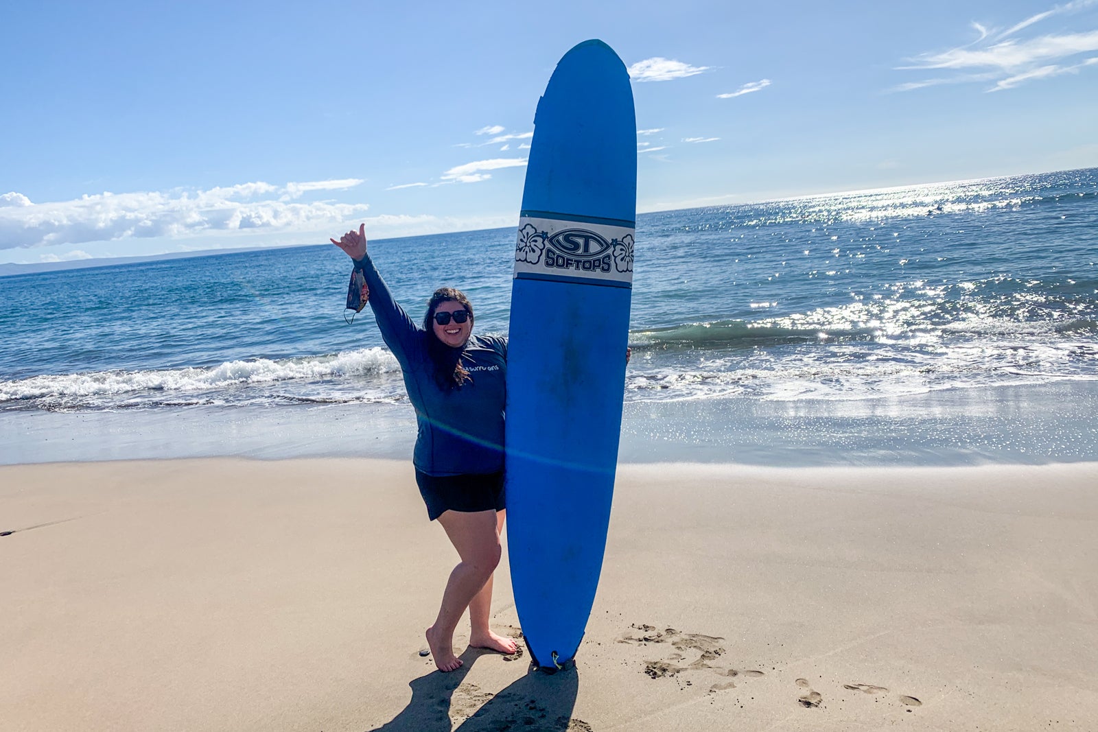 Madison with a surfboard on a beach in Maui, Hawaii