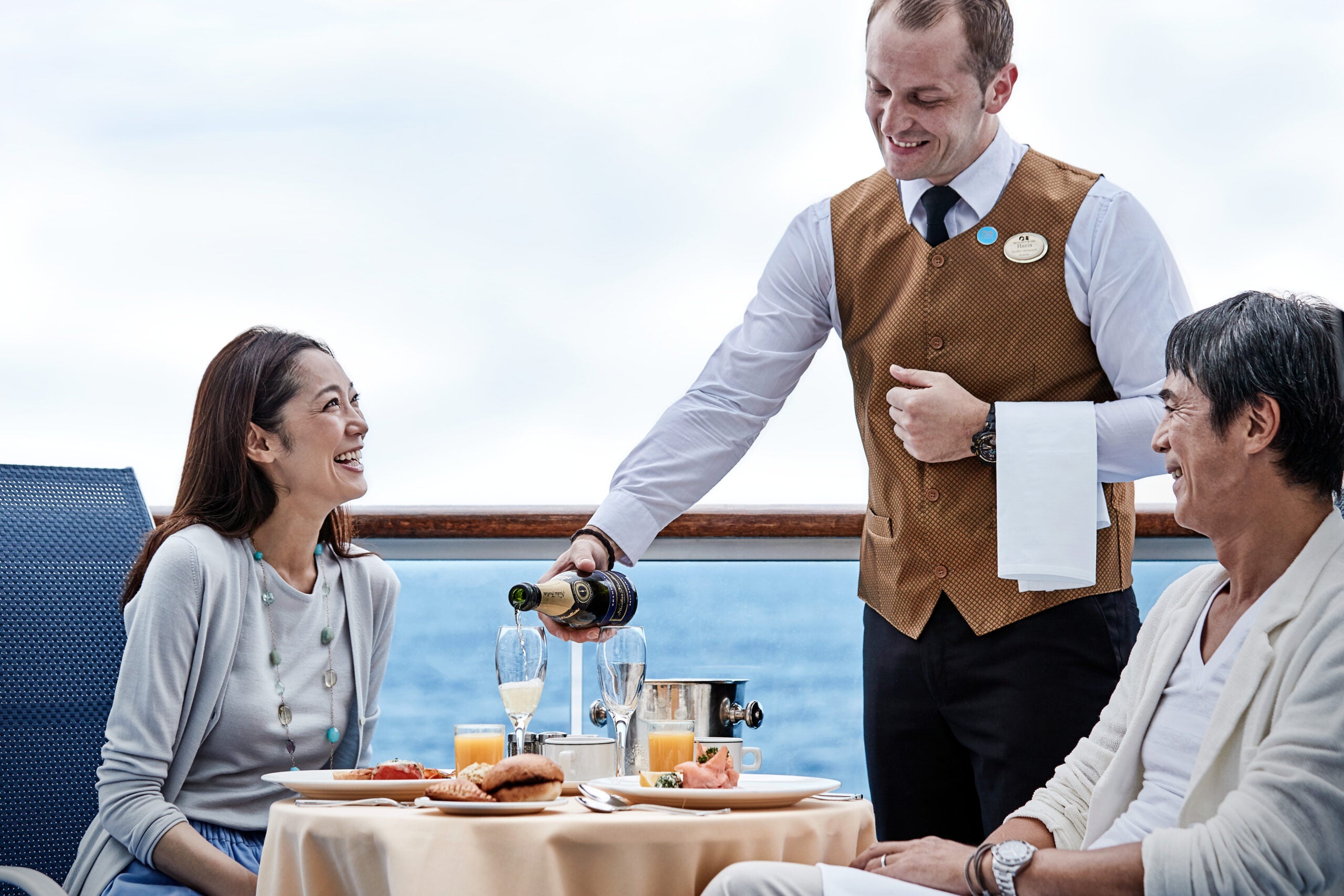 couple being served dinner on a cruise ship balcony
