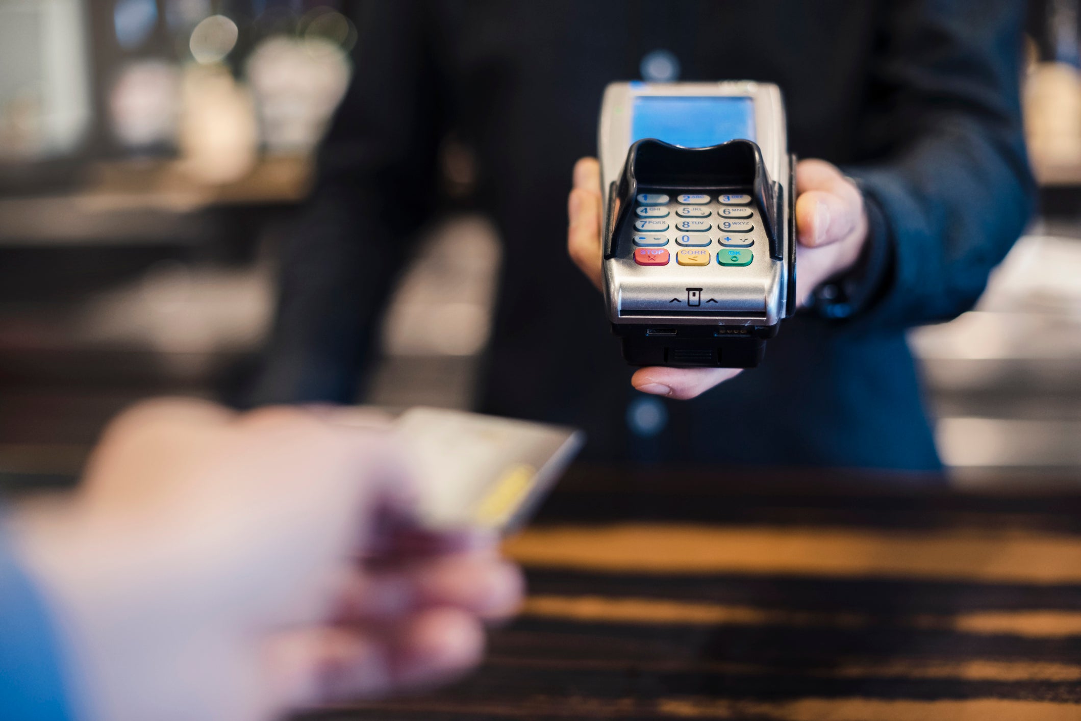 An unseen person holds a credit card machine so another person can make a payment