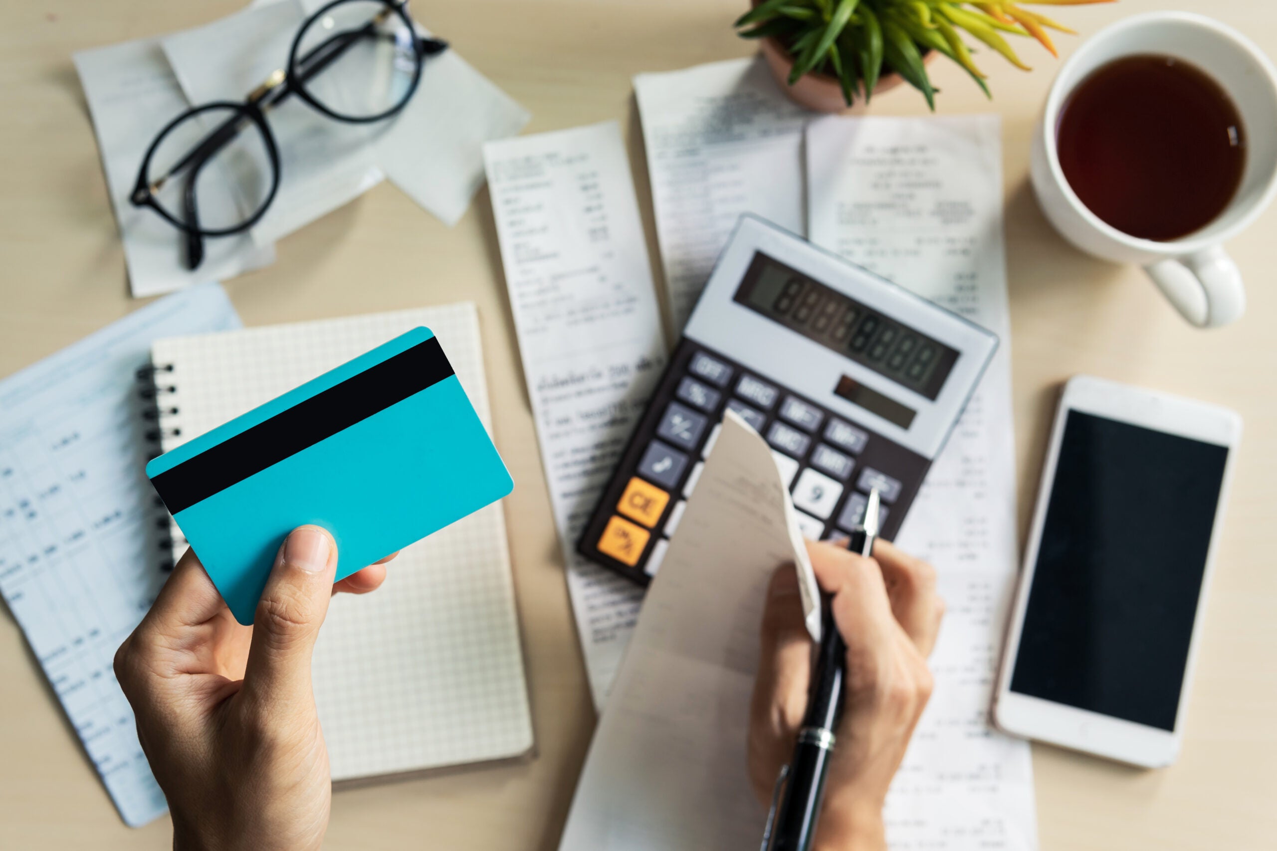 A person looking at their credit card while using a calculator