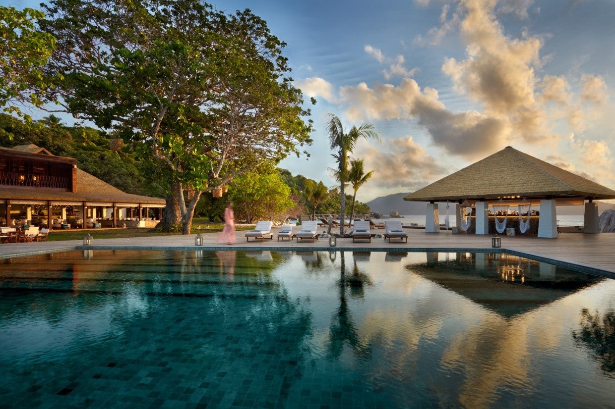 A person walks by a tranquil pool at a luxury resort 