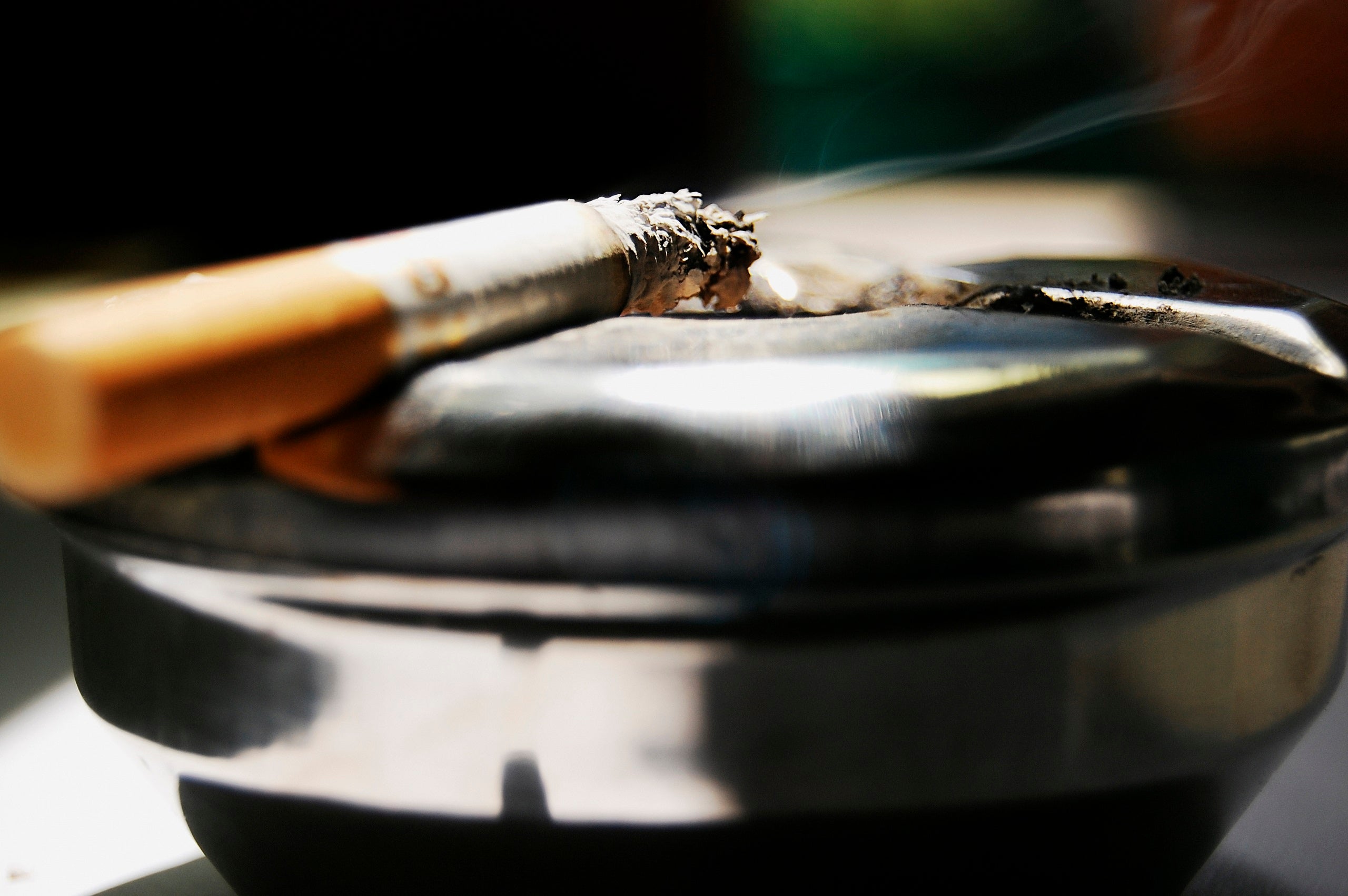 Closeup of a smoking cigarette resting on an ashtray