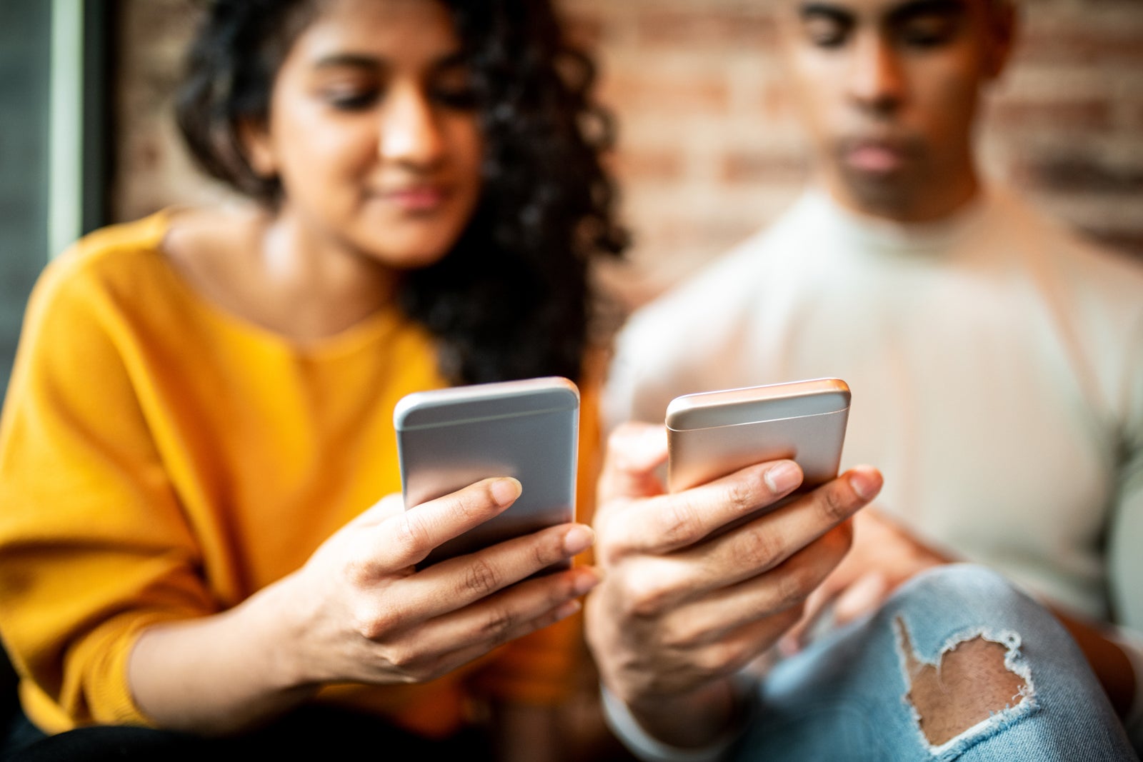 two friends both look at their smart phones together