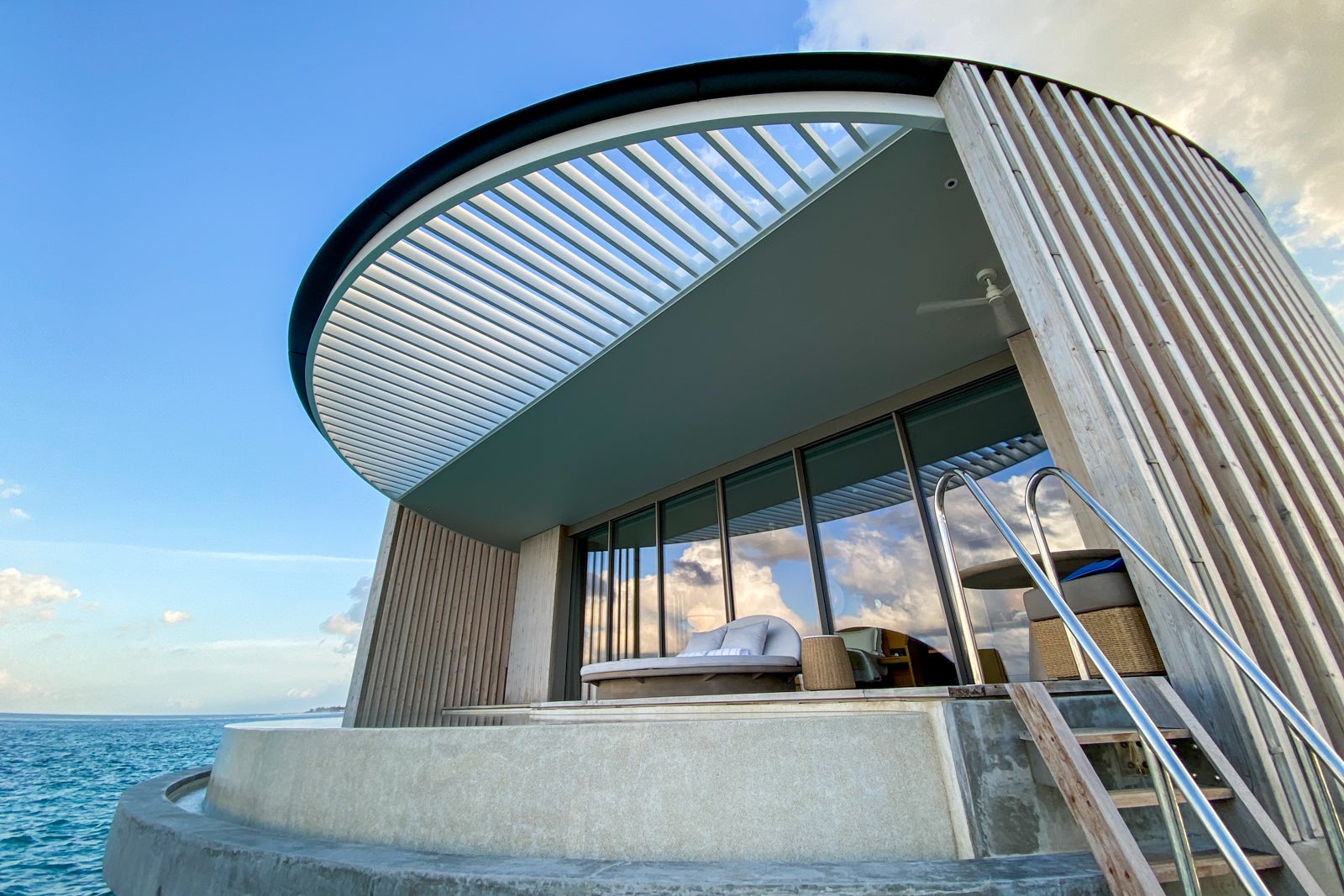 a ladder from the ocean leads up to an overwater bungalow