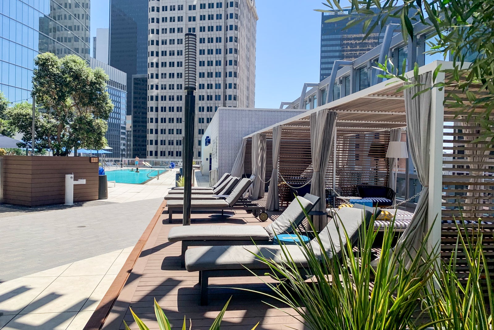 lounge chairs flank a rooftop hotel pool surrounded by skyscrapers