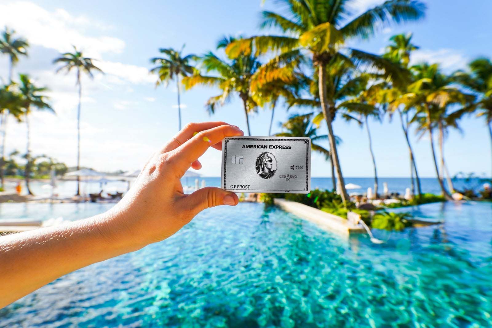 a hand holds a credit card near a swimming pool