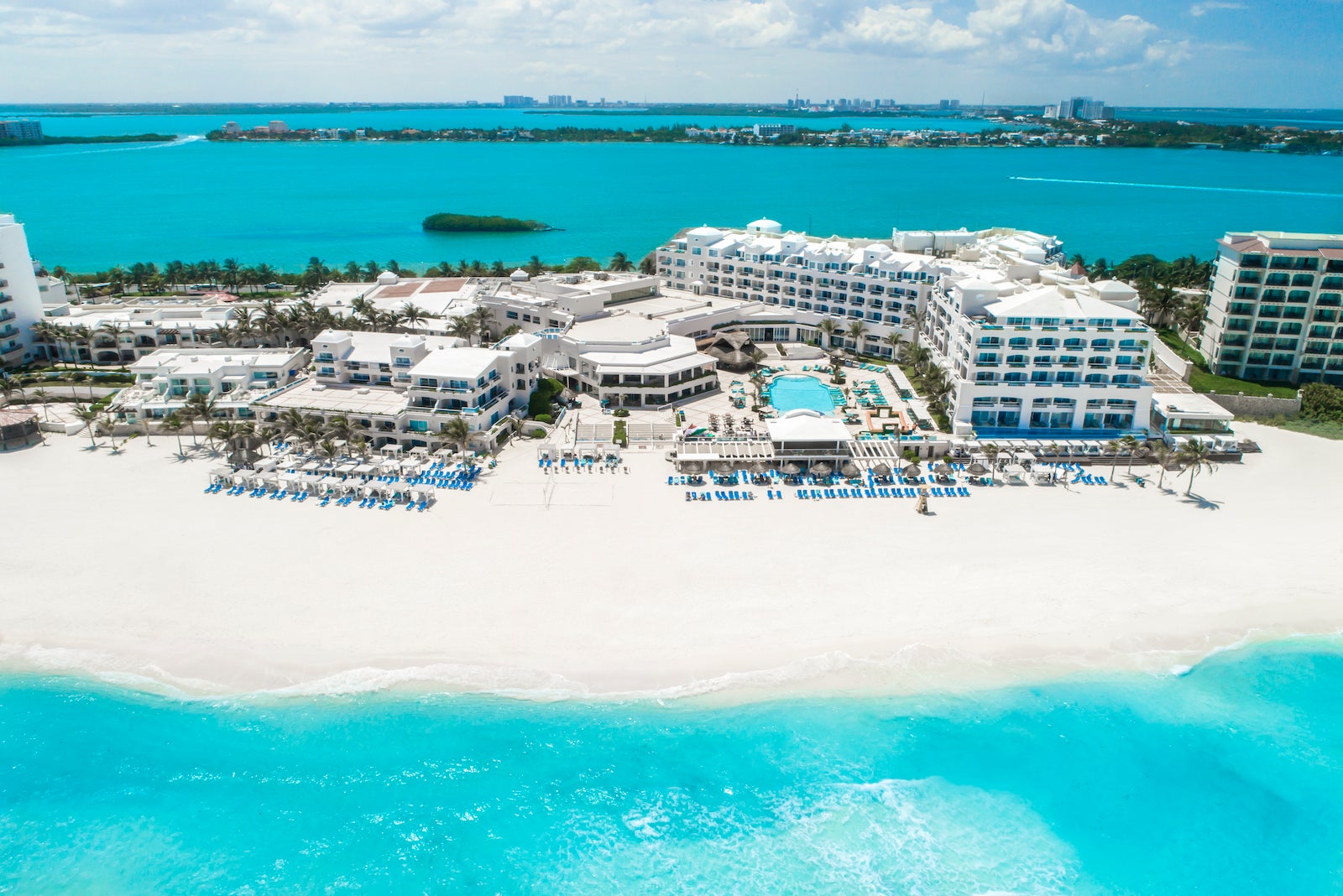 large white resort on white sandy beach surrounded by clear blue waters