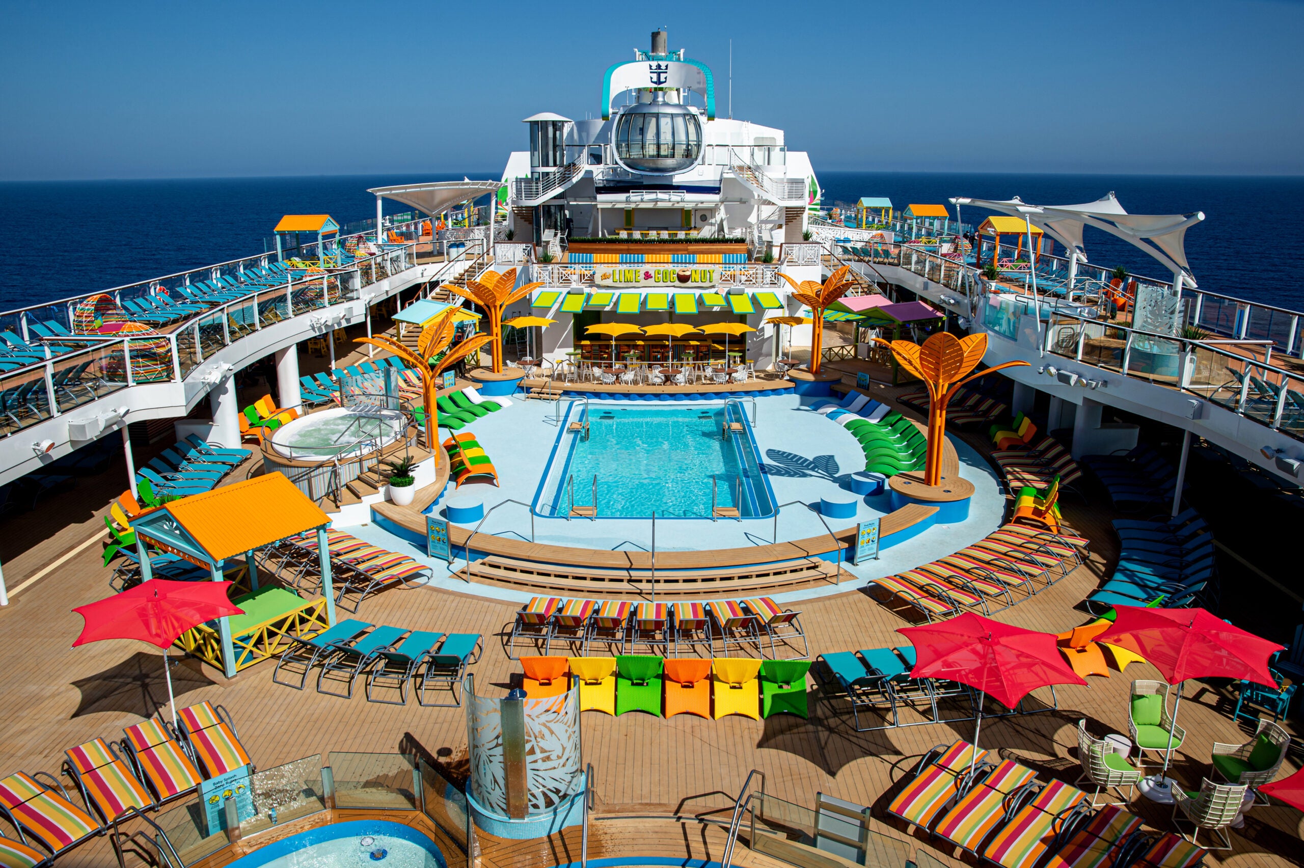 Royal Caribbean cruise ship pool deck with colored lounge chairs and a swimming pool.