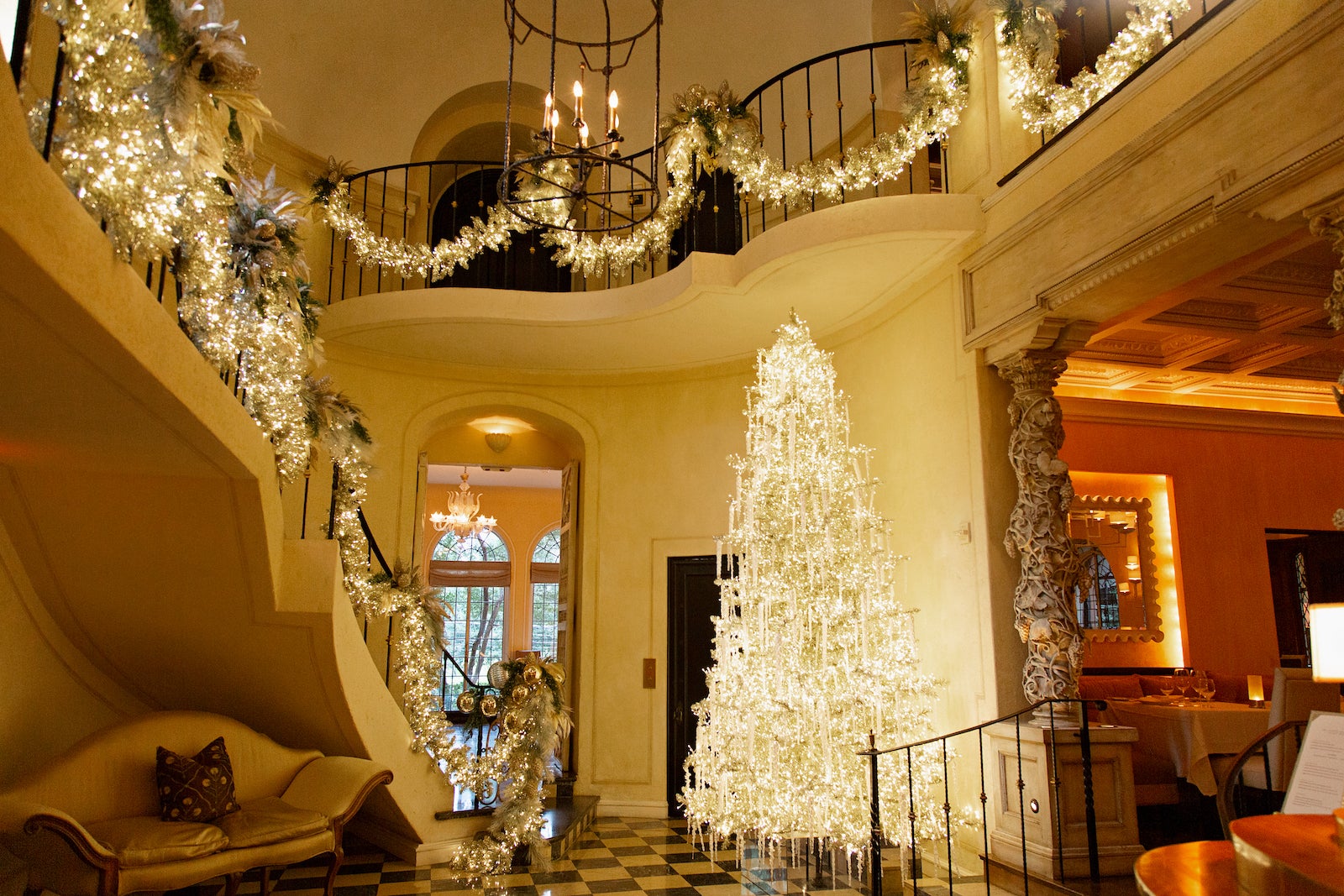 large room with white Christmas tree, balcony and staircase