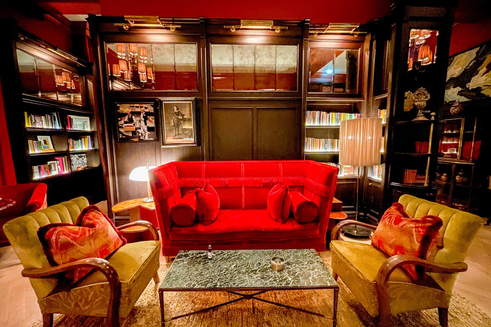 a dark library with a red velvet sofa