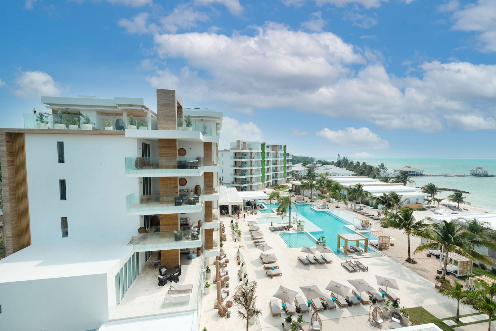 Aerial photo of resort with palm trees and swimming pool near white-sand beaches and ocean