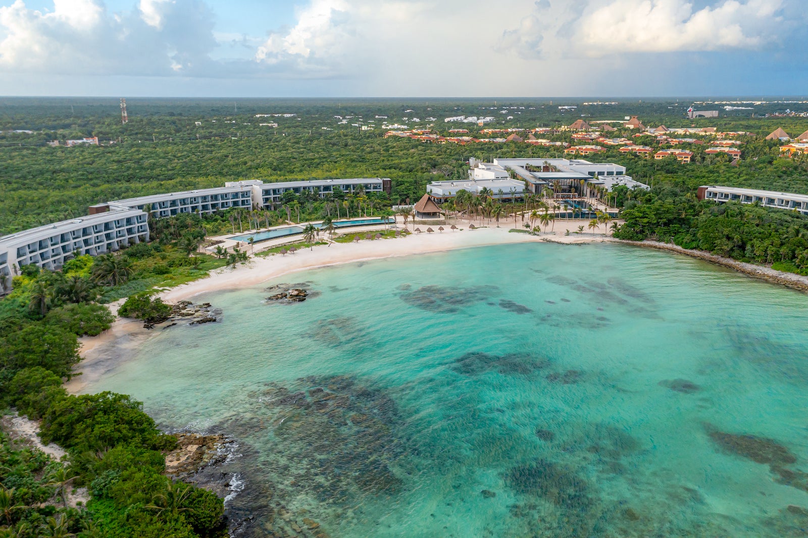 Aerial photo of large white resort surrounded by bay with turquoise water