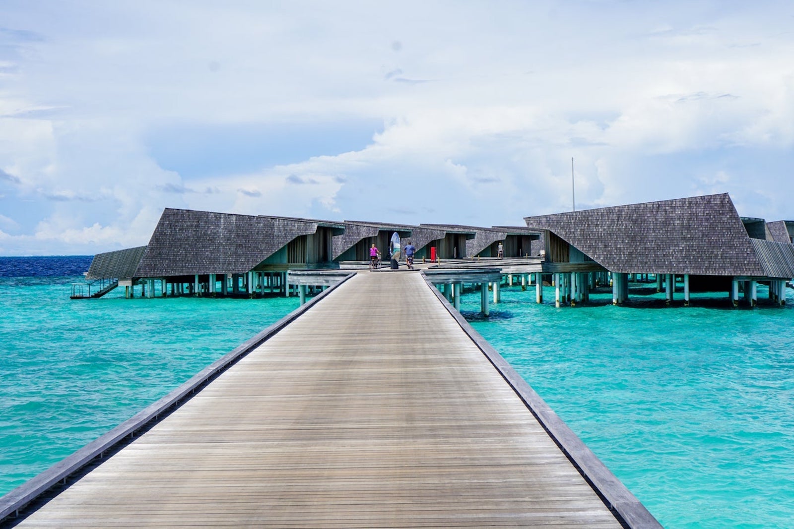 deck leading to overwater bungalows surrounded by beautiful blue water