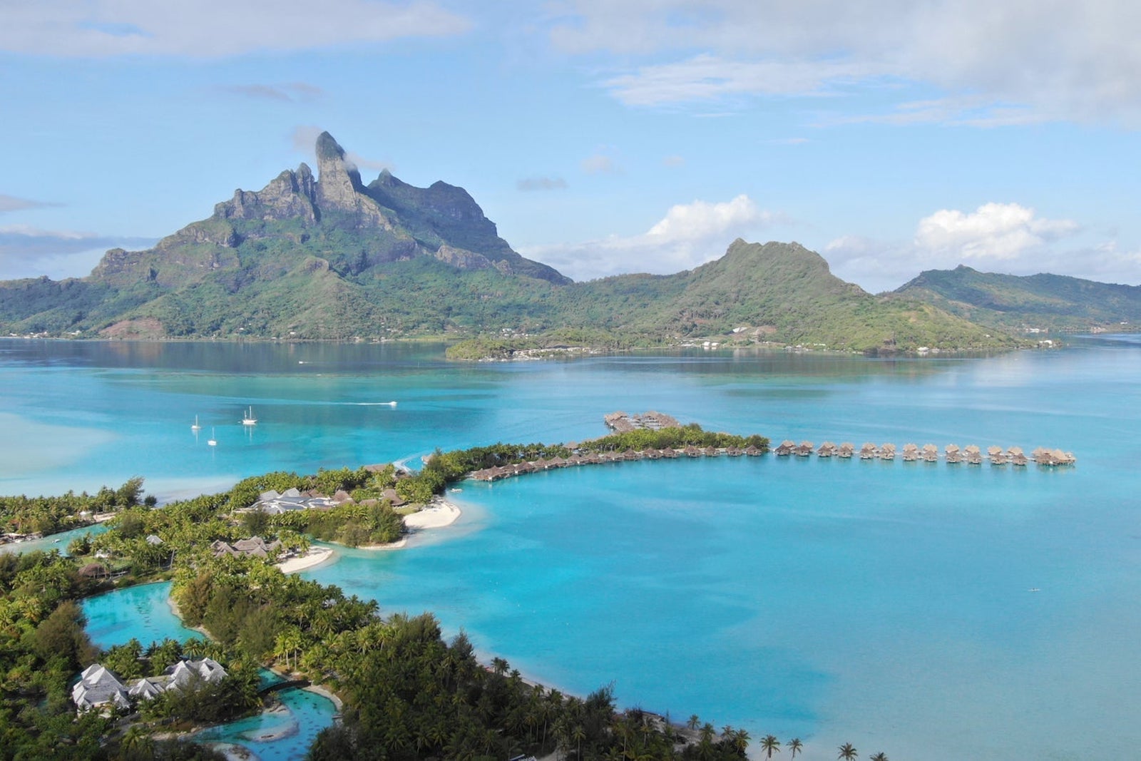 mountain and overwater bungalows in crystal blue waters