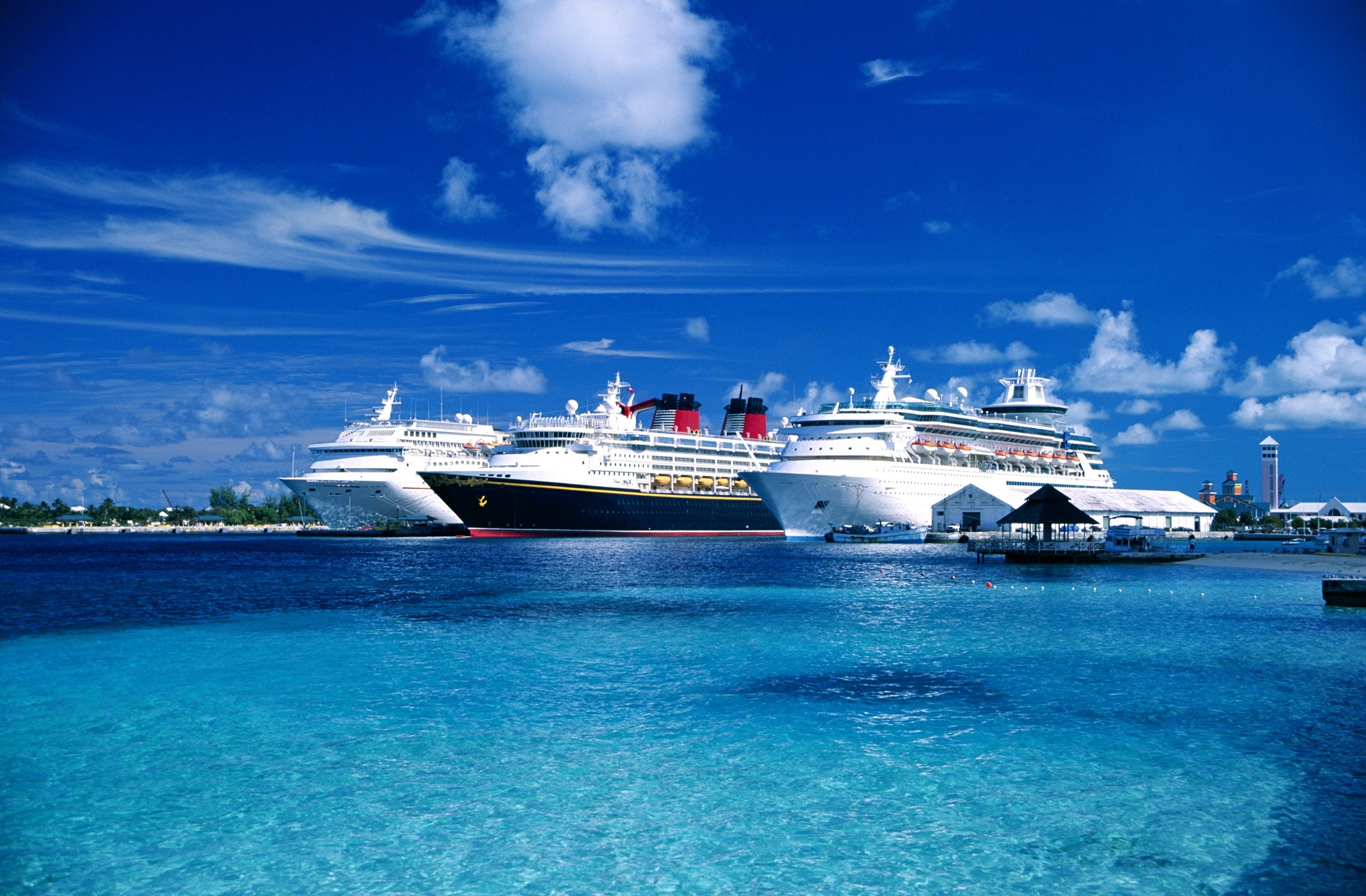 Three cruise ships docked side by side in blue water