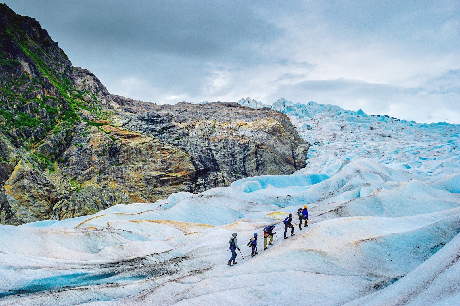 Five people hiking up a glacier in Alaska