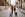 A view from behind of a couple walking on cobble streets with two carry-on sized luggage with wheels.