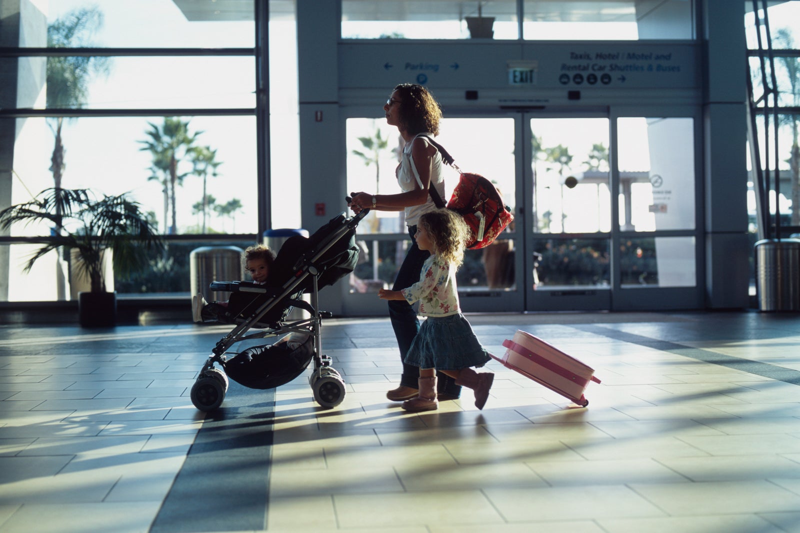 Mom with young daughter and baby in stroller walking through airport