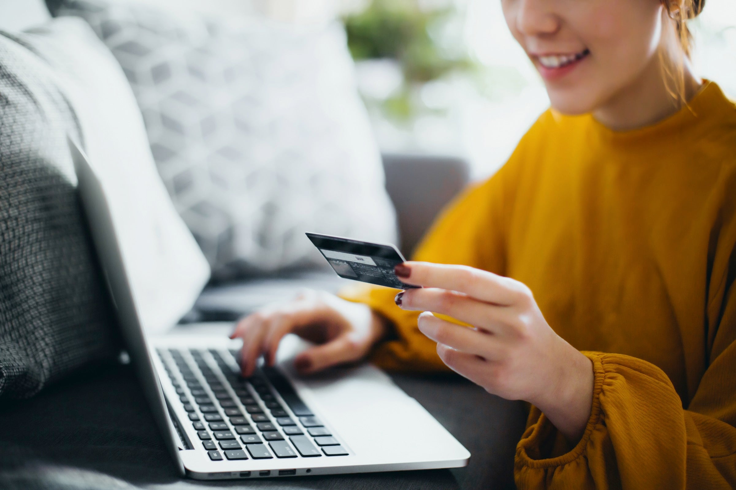 Person holding credit card over a laptop