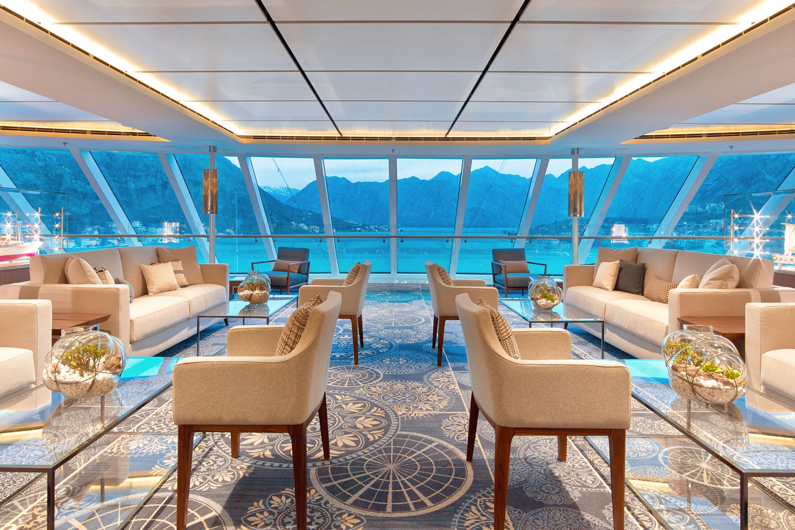 Cruise ship lounge with floor to ceiling windows and seating areas